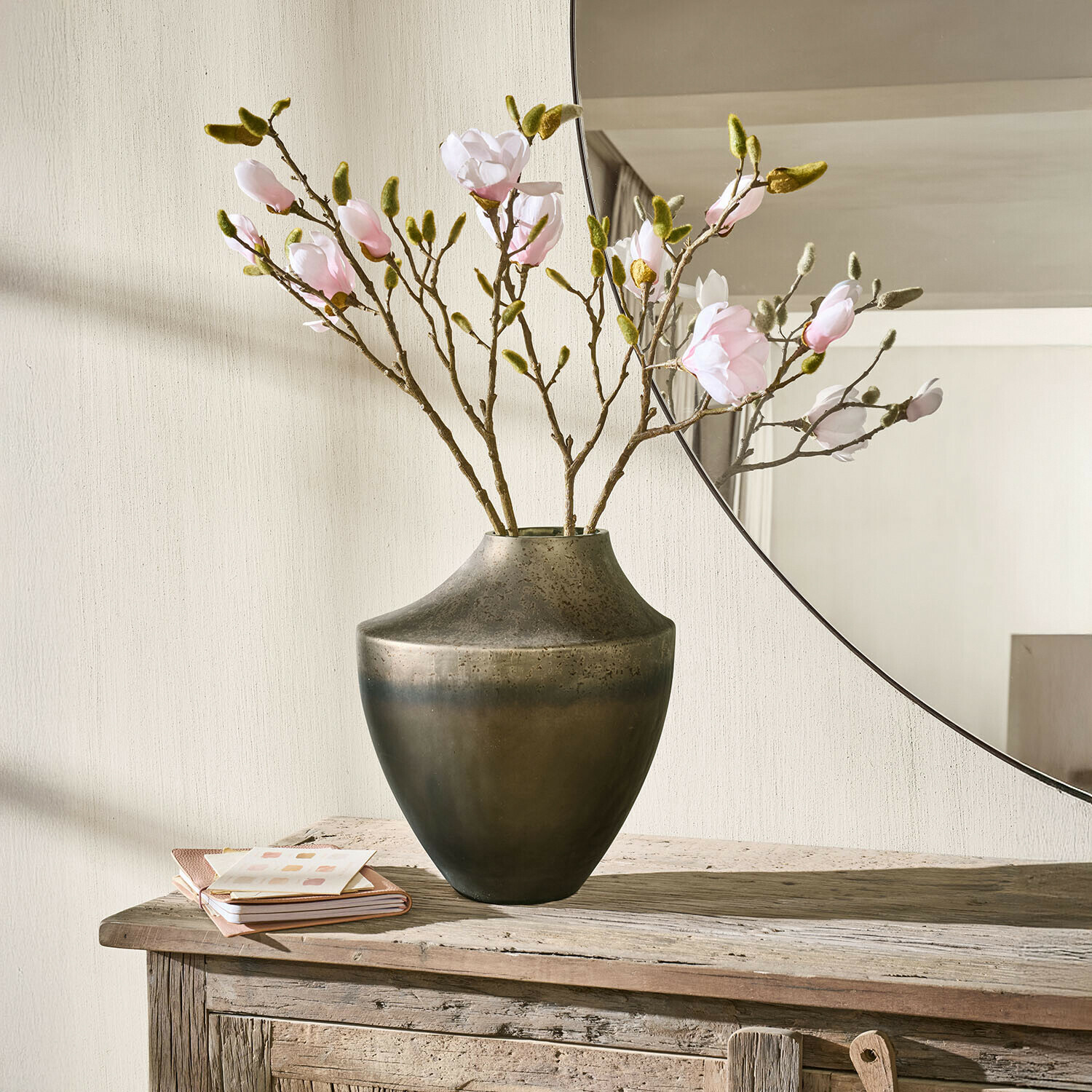 Vaso Tavris Vaso in metallo marrone scuro con rami di fiori rosa su tavolo in legno rustico