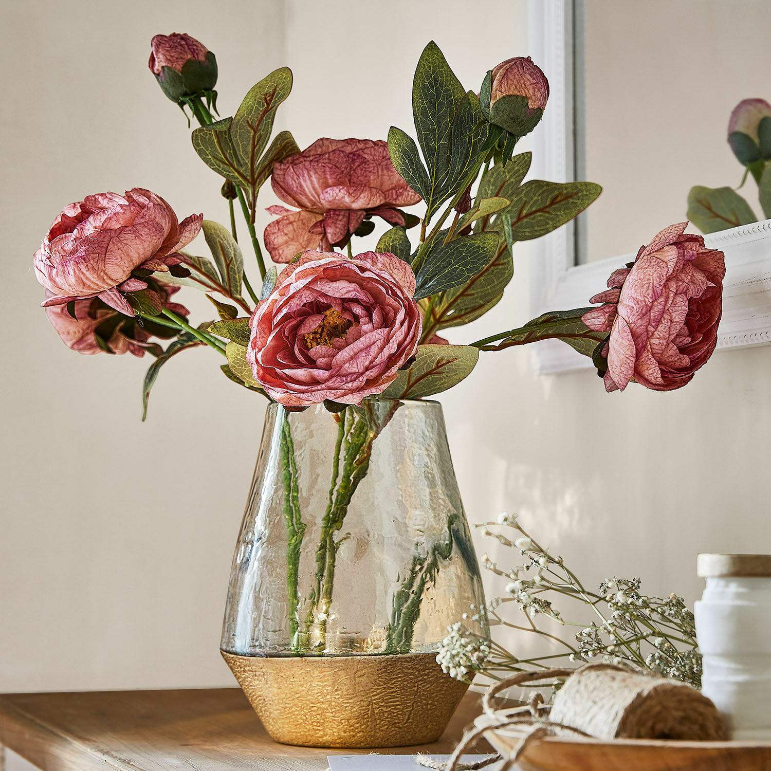 Set di 3 fiori decorativi Gilgandra Vaso in vetro con base dorata testurizzata e fiori decorativi rosa su tavolo in legno