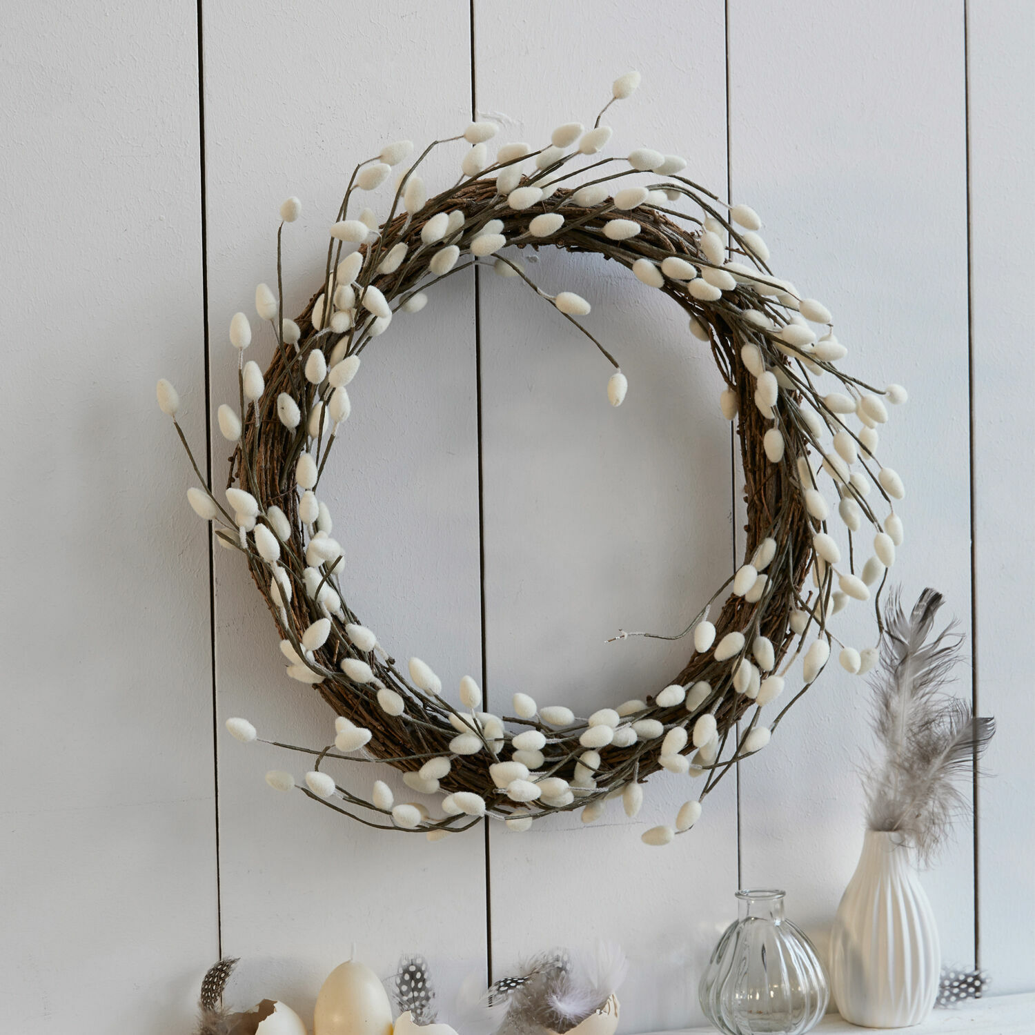 Ghirlanda Prapante Corona decorativa di rami con boccioli bianchi soffici su parete chiara, decorazione primaverile