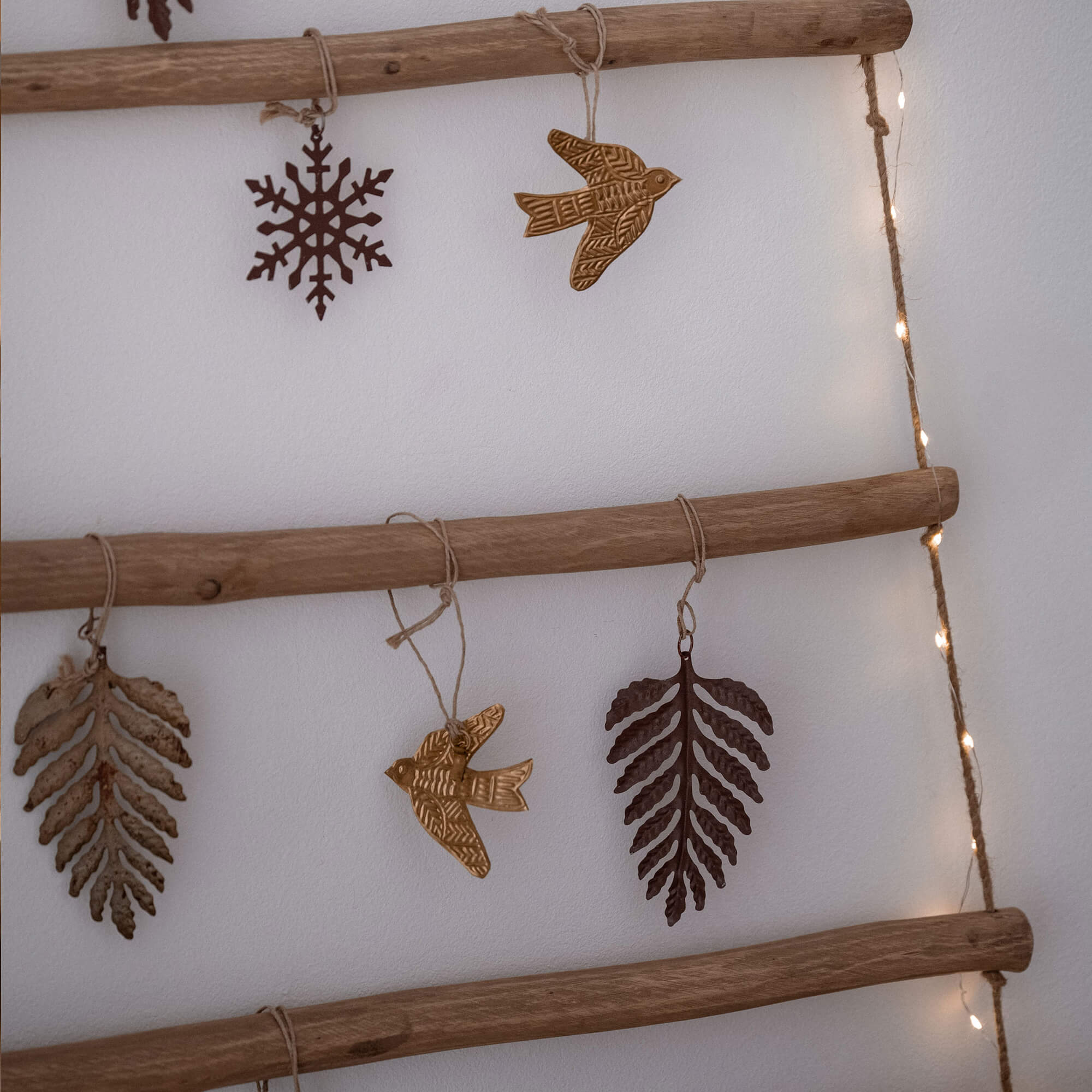 Decorazioni natalizie in metallo a forma di foglie, uccelli e fiocchi appese a scala in legno