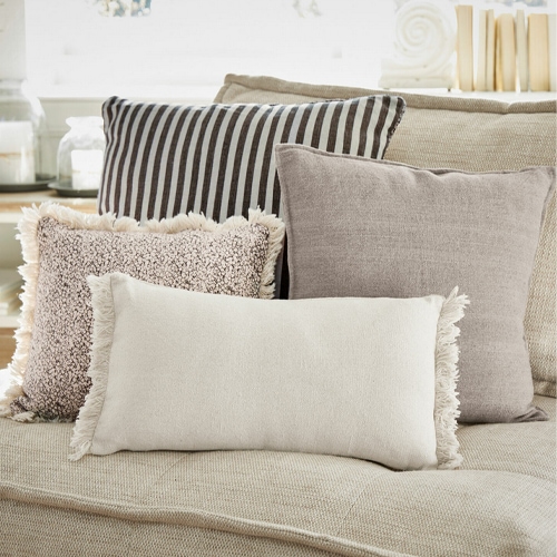 Set di cuscini decorativi beige e marroni su divano beige, materiali morbidi, decorazione soggiorno