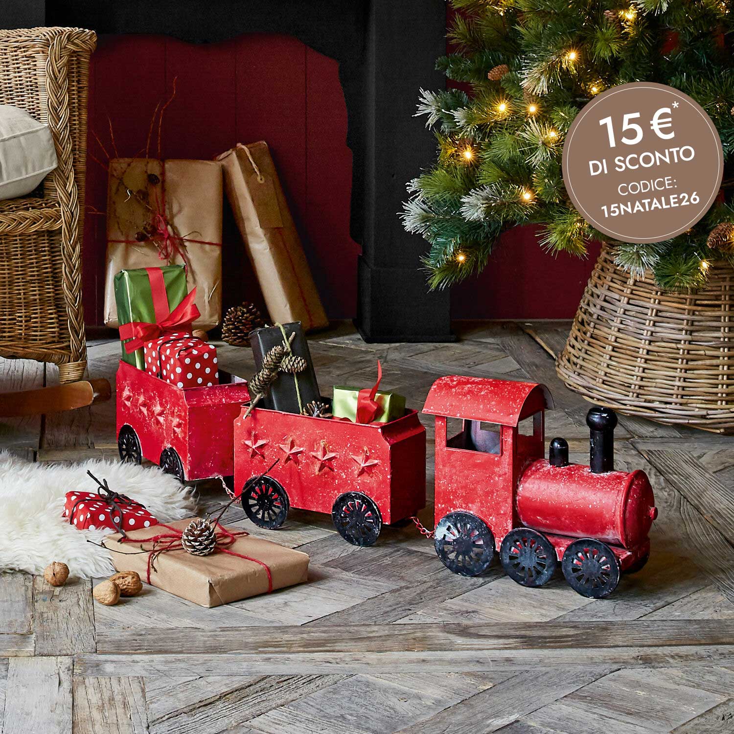 Treno decorativo in metallo rosso con stelle, pieno di regali, decorazione natalizia sotto l'albero illuminato