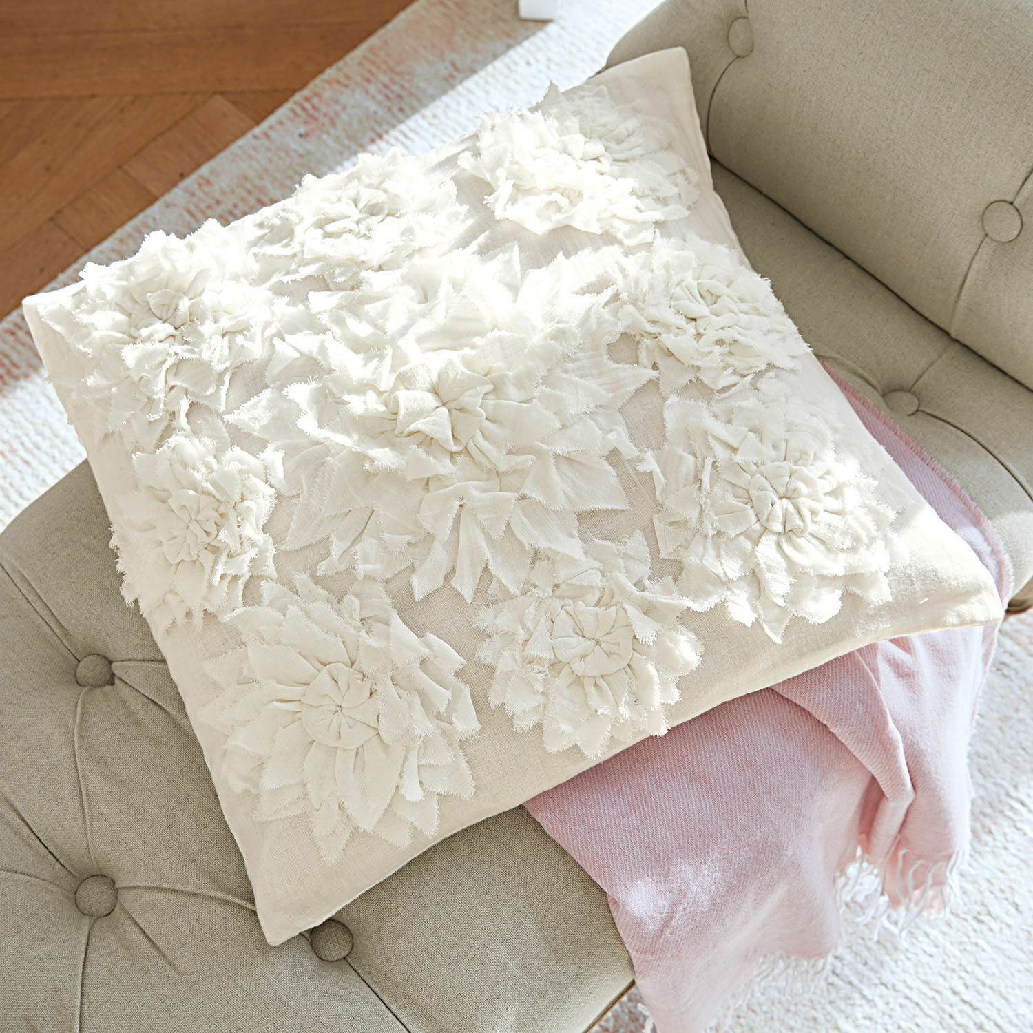 Copricuscino Dorevil Cuscino decorativo beige con applicazioni floreali in tessuto su divano grigio con coperta rosa