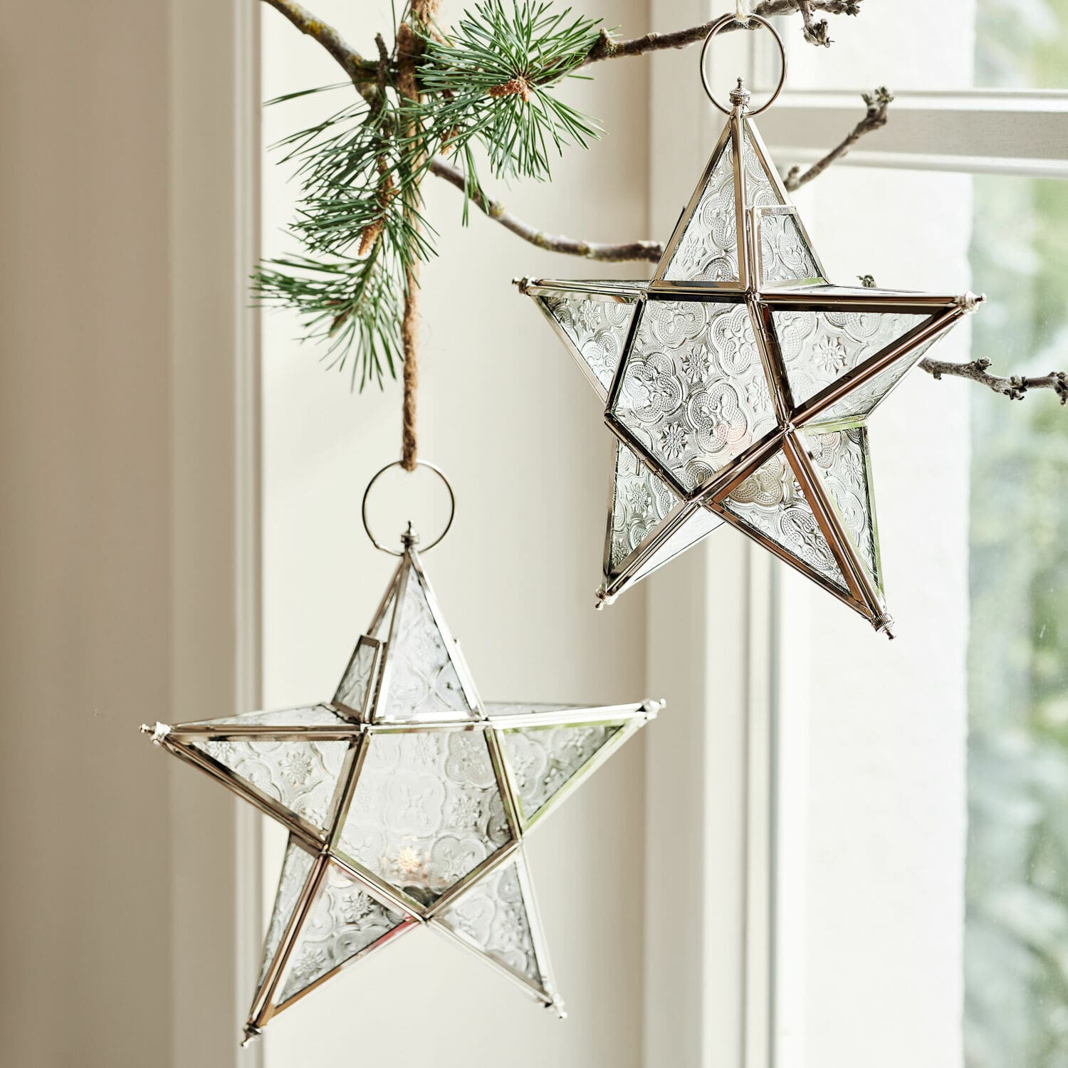 Coppia di portacandele Kian Stelle decorative in vetro con cornice metallica argento appese a un ramo di pino