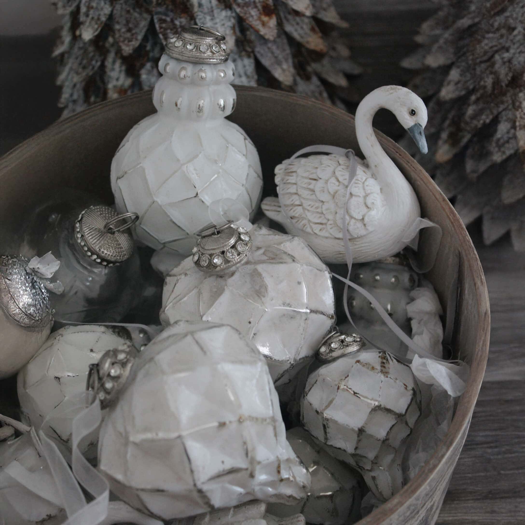 Decorazioni natalizie bianche in ceramica e vetro in una ciotola di legno, ornamenti invernali