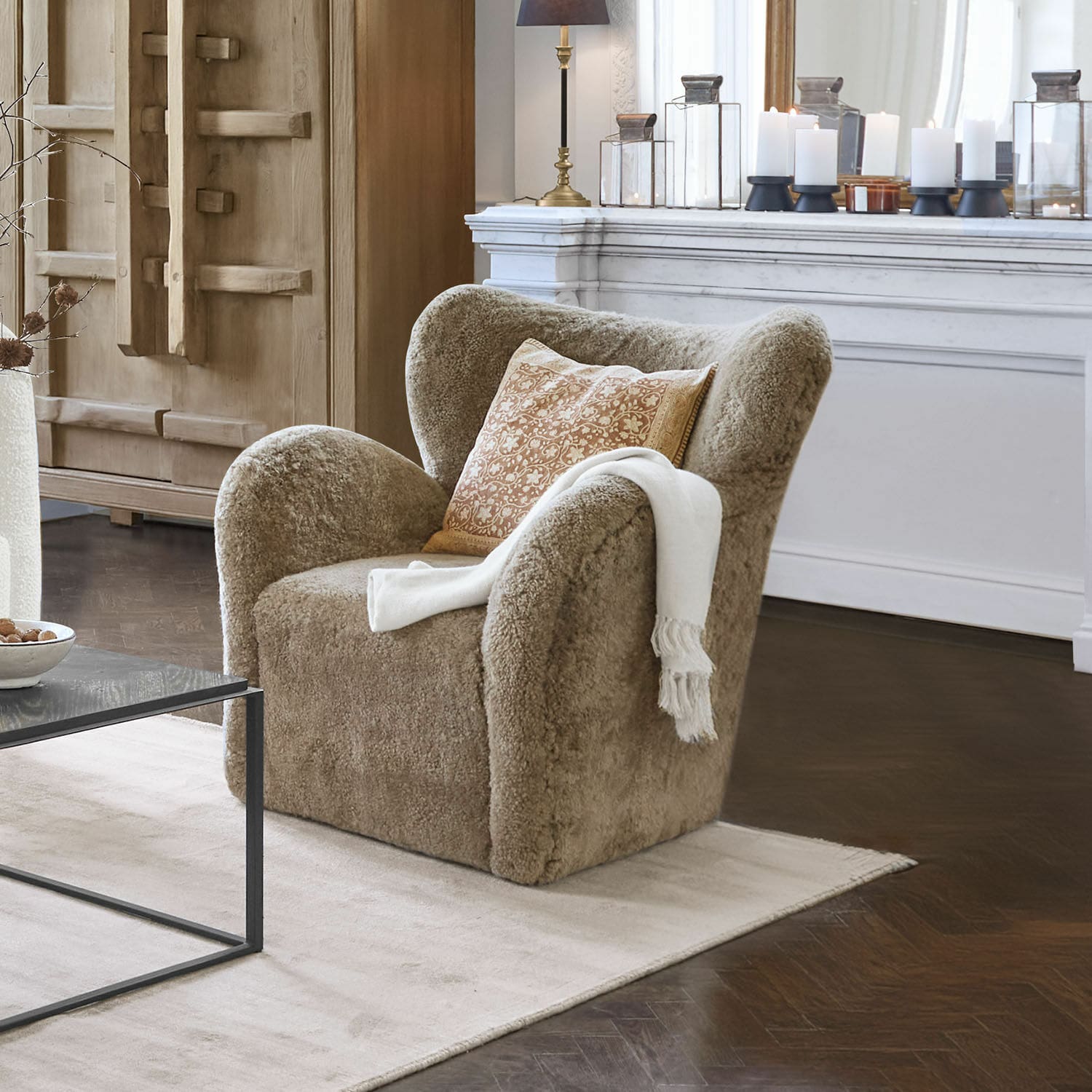 Poltrona Ambrécourt Poltrona beige in materiale morbido con cuscino e coperta bianca in soggiorno elegante