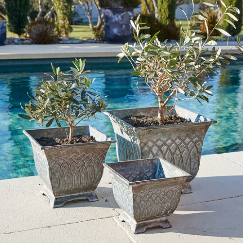 Tre vasi in metallo grigio stile vintage vicino alla piscina, ideali per piante da giardino