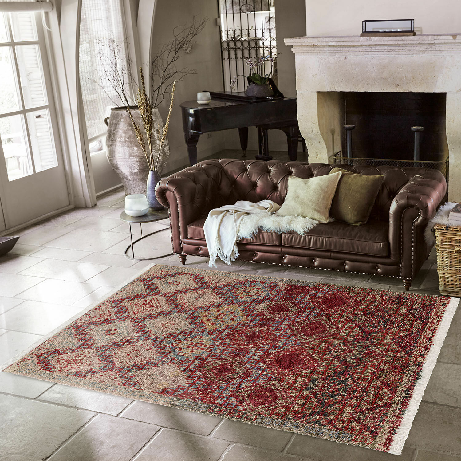 Tappeto Thalivine Tappeto decorativo rosso e beige con motivi su pavimento in pietra vicino a divano in pelle marrone