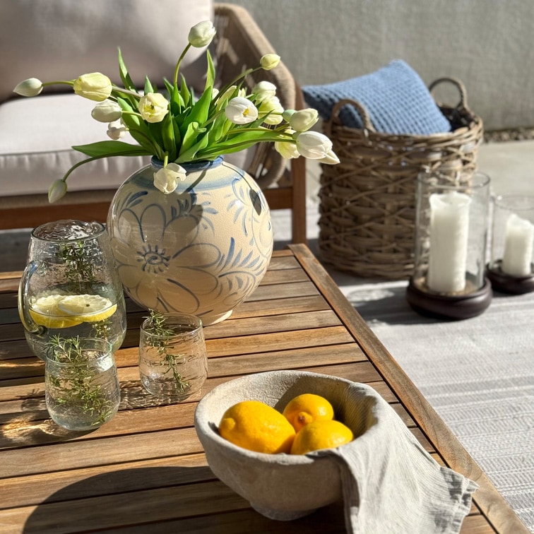 Vaso decorativo in ceramica con motivo floreale e tulipani bianchi su tavolo in legno in terrazza