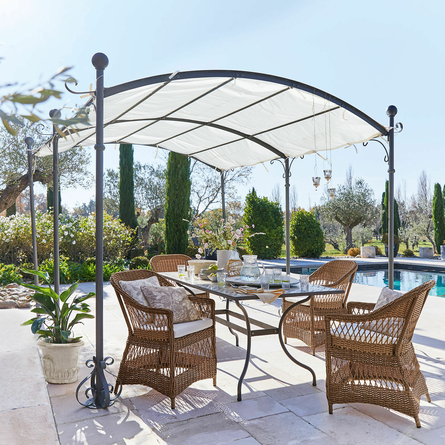 Pergola Yarl Set di mobili da giardino in rattan marrone sotto un padiglione metallico bianco vicino alla piscina