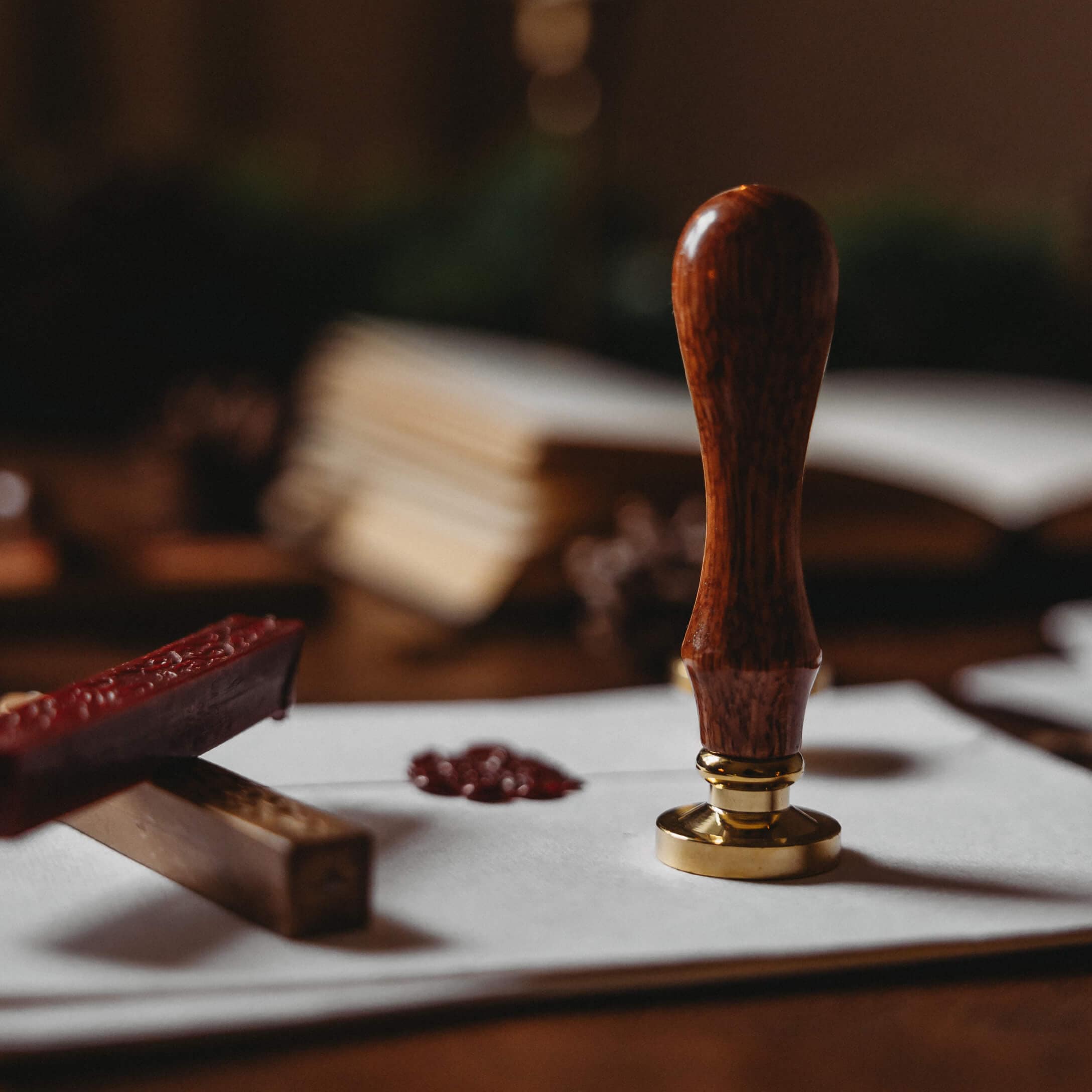 Sigillo per lettere con manico in legno e base in ottone su busta bianca con cera rossa