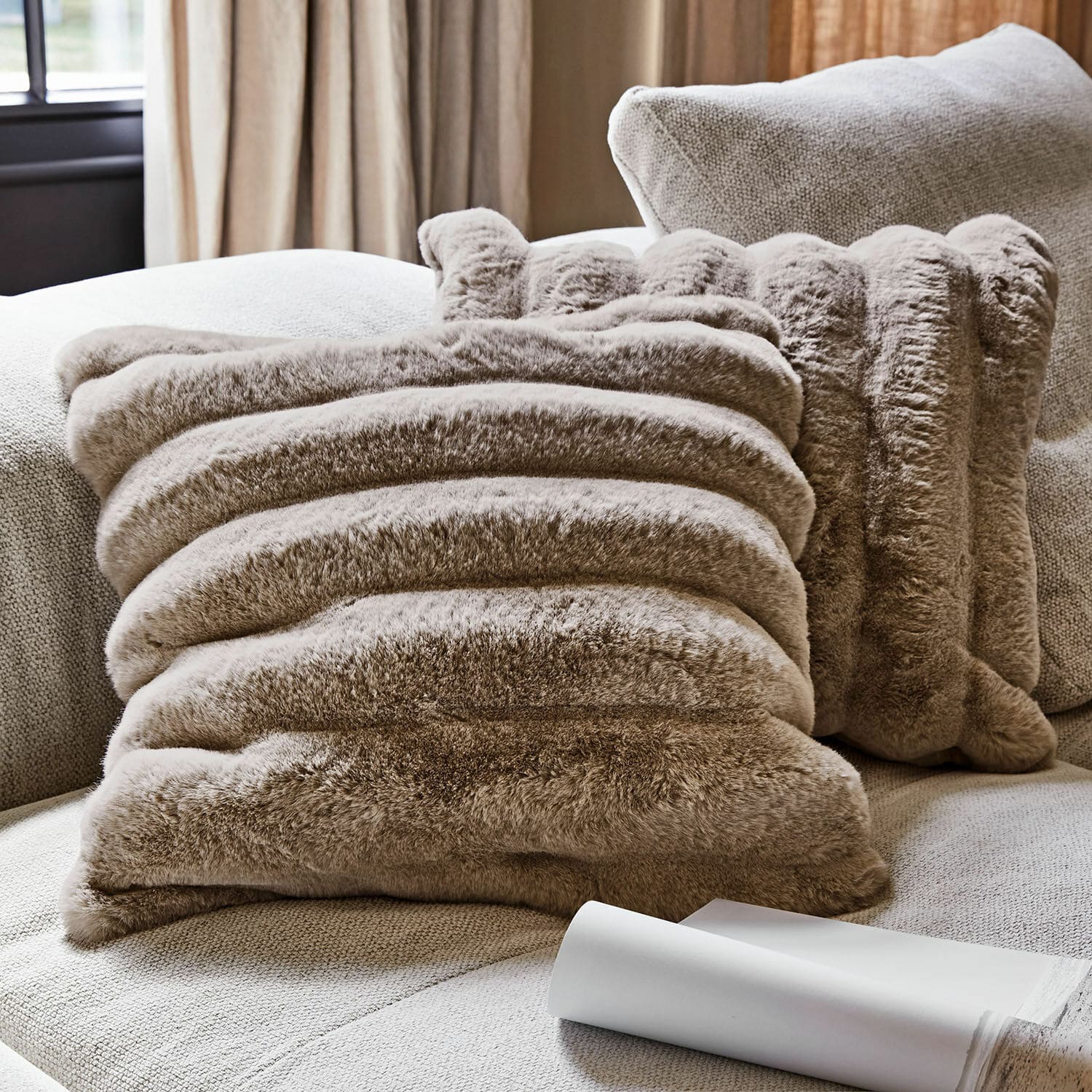 Coppia di copricuscini Caelira Cuscino decorativo in pelliccia sintetica beige su divano chiaro per soggiorno accogliente
