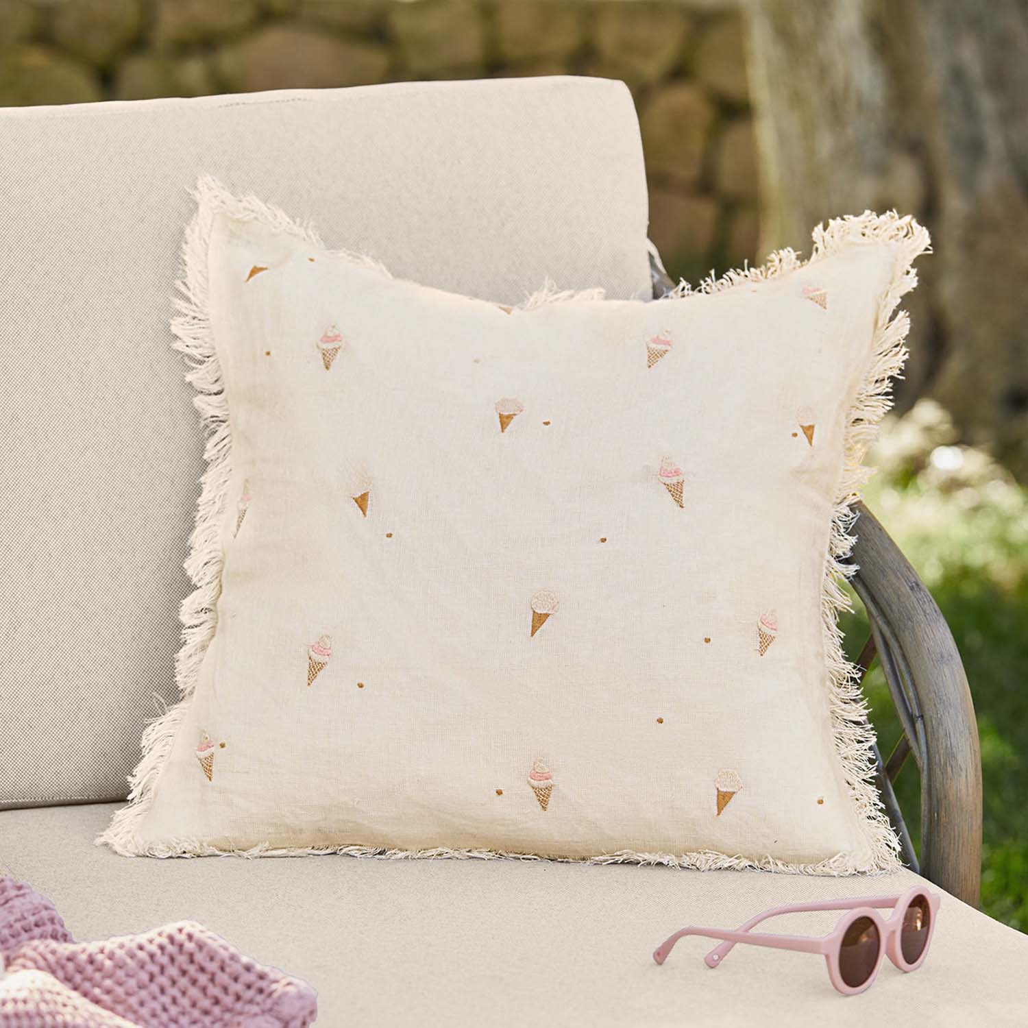 Cuscino in lino beige con frange e motivo gelati pastello su divano da giardino