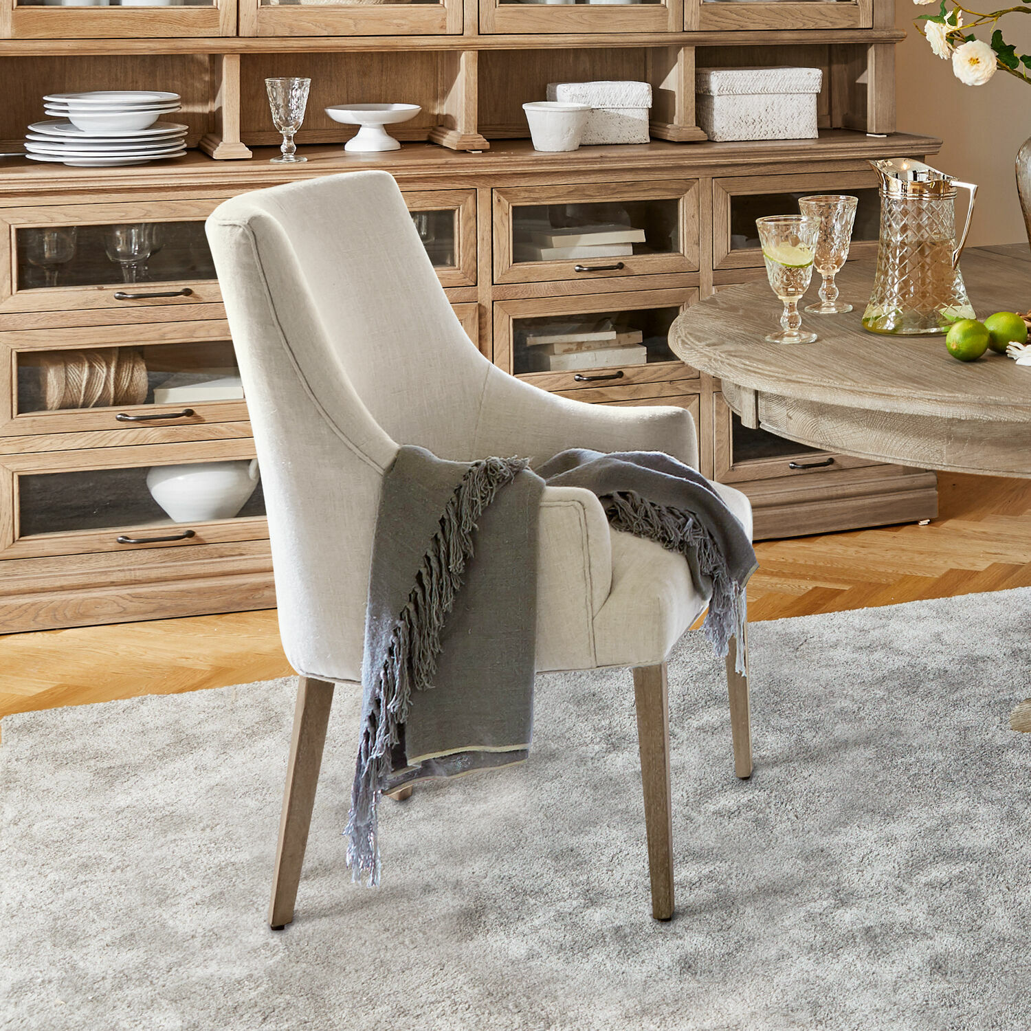 Sedia Hyeres Poltrona beige imbottita con gambe in legno e coperta grigia in soggiorno accogliente con mobile in legno