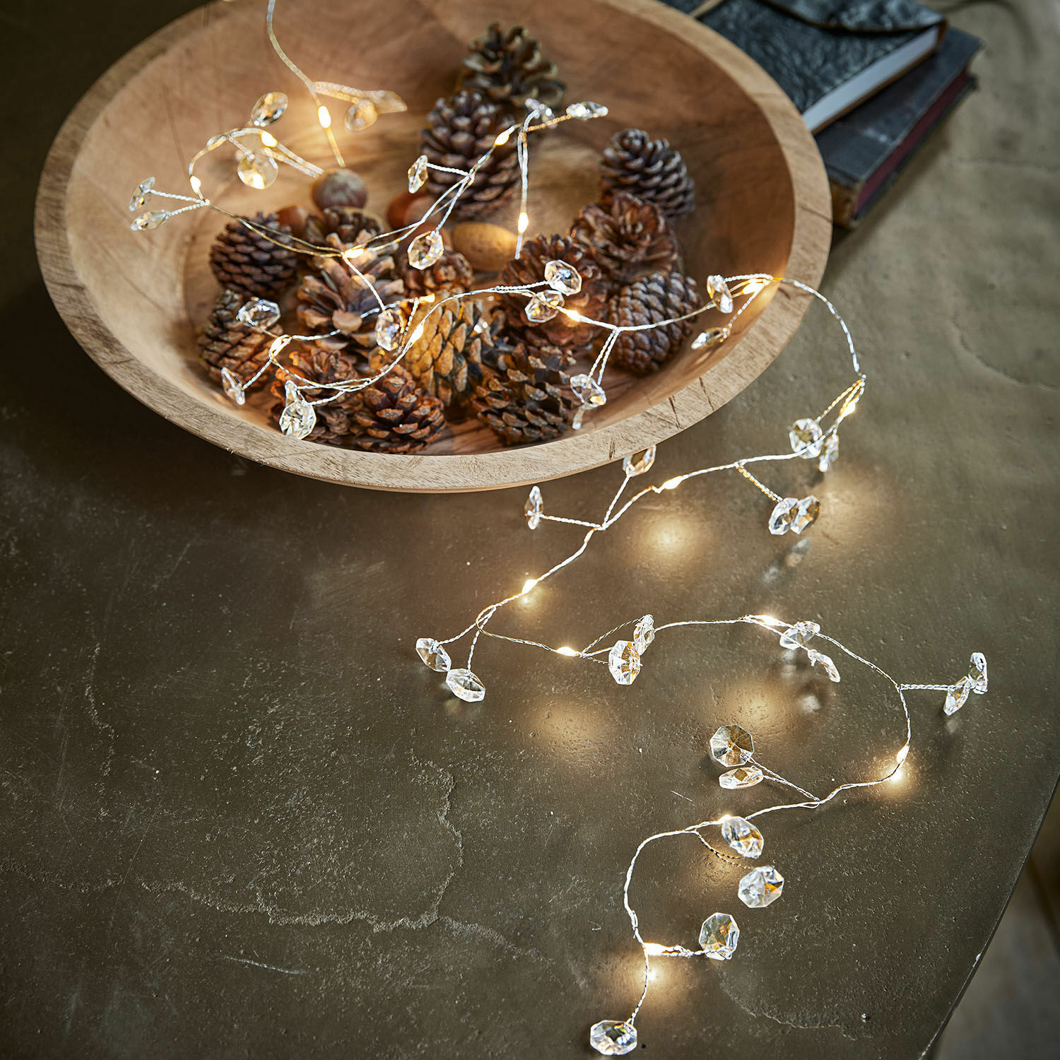 Catena luminosa a LED Laurits Ciotola in legno con pigne e delicata catena luminosa con decorazioni di cristallo su tavolo