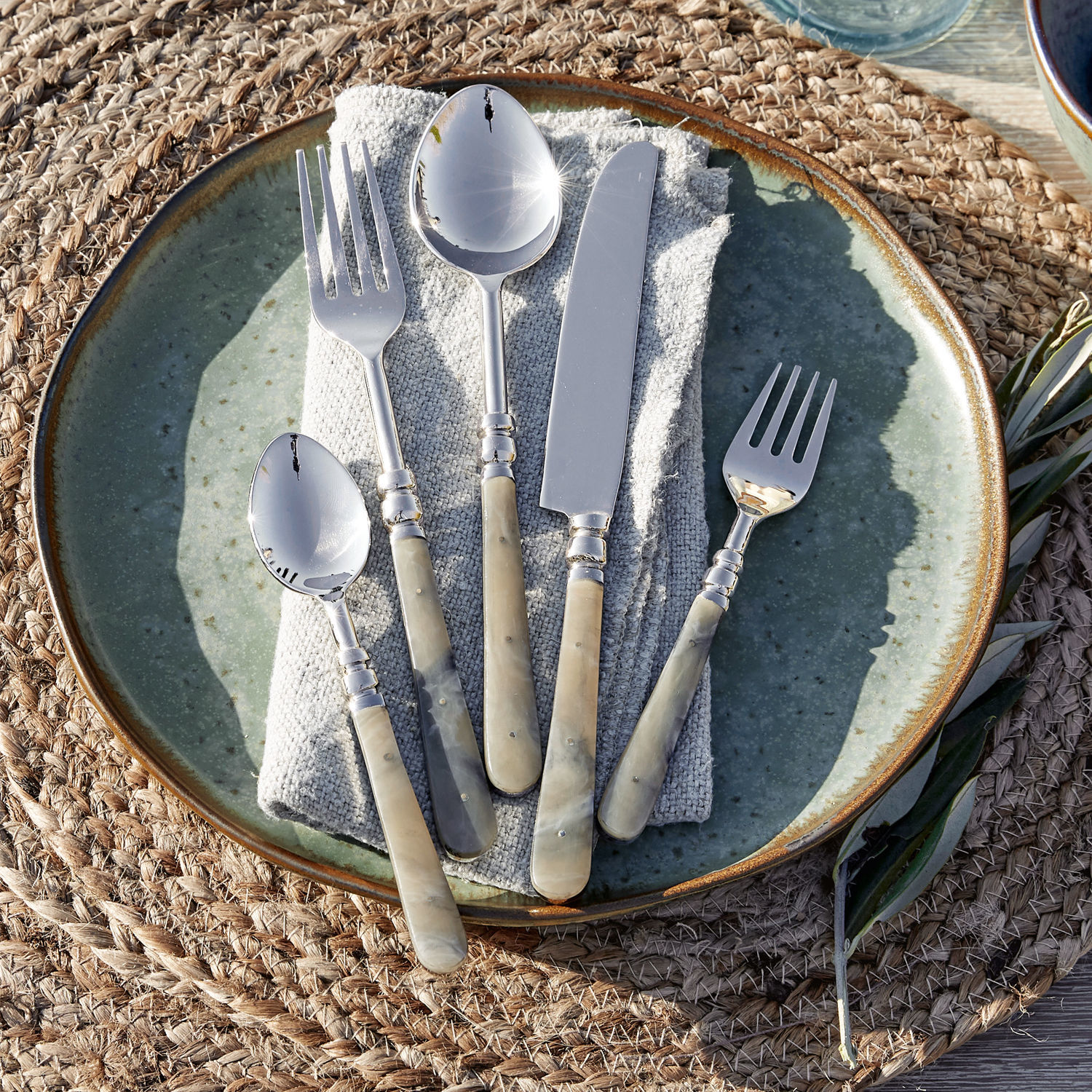 Set di 5 posate Kumar Set di posate con manici in madreperla beige su piatto verde, elegante decorazione da tavola