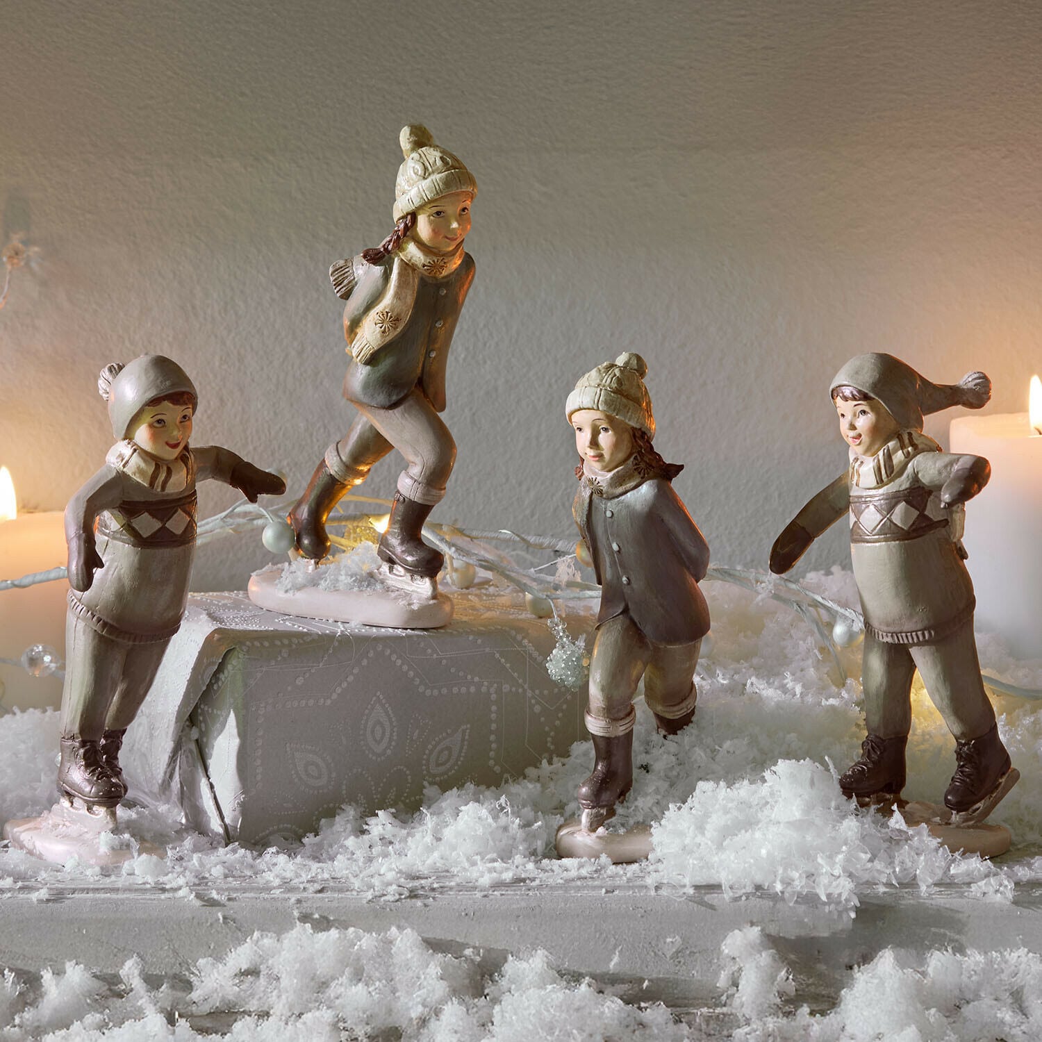 Set di 4 statuine Mériot Figure in ceramica di bambini che pattinano in beige e grigio su tavolo decorato con neve artificiale