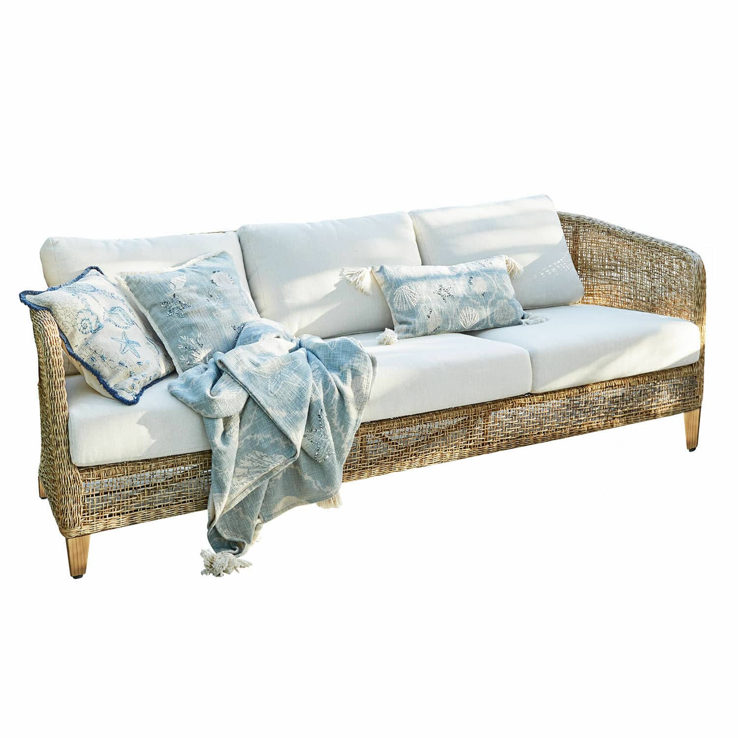 Divano Clarivaux Divano in rattan con cuscini crema e coperta blu con motivi marini per soggiorno