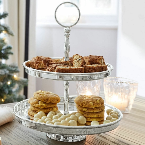 Porta dolci a due livelli in argento per biscotti e dolcetti su tavolo in legno con decorazioni natalizie