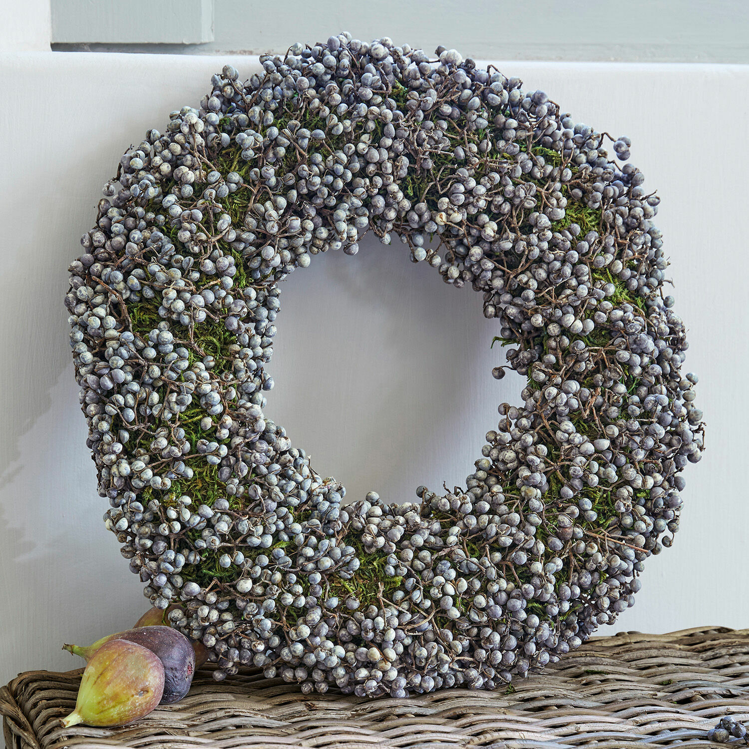 Ghirlanda Elly Corona decorativa con bacche secche e muschio verde su tavolo in vimini, decorazione stagionale