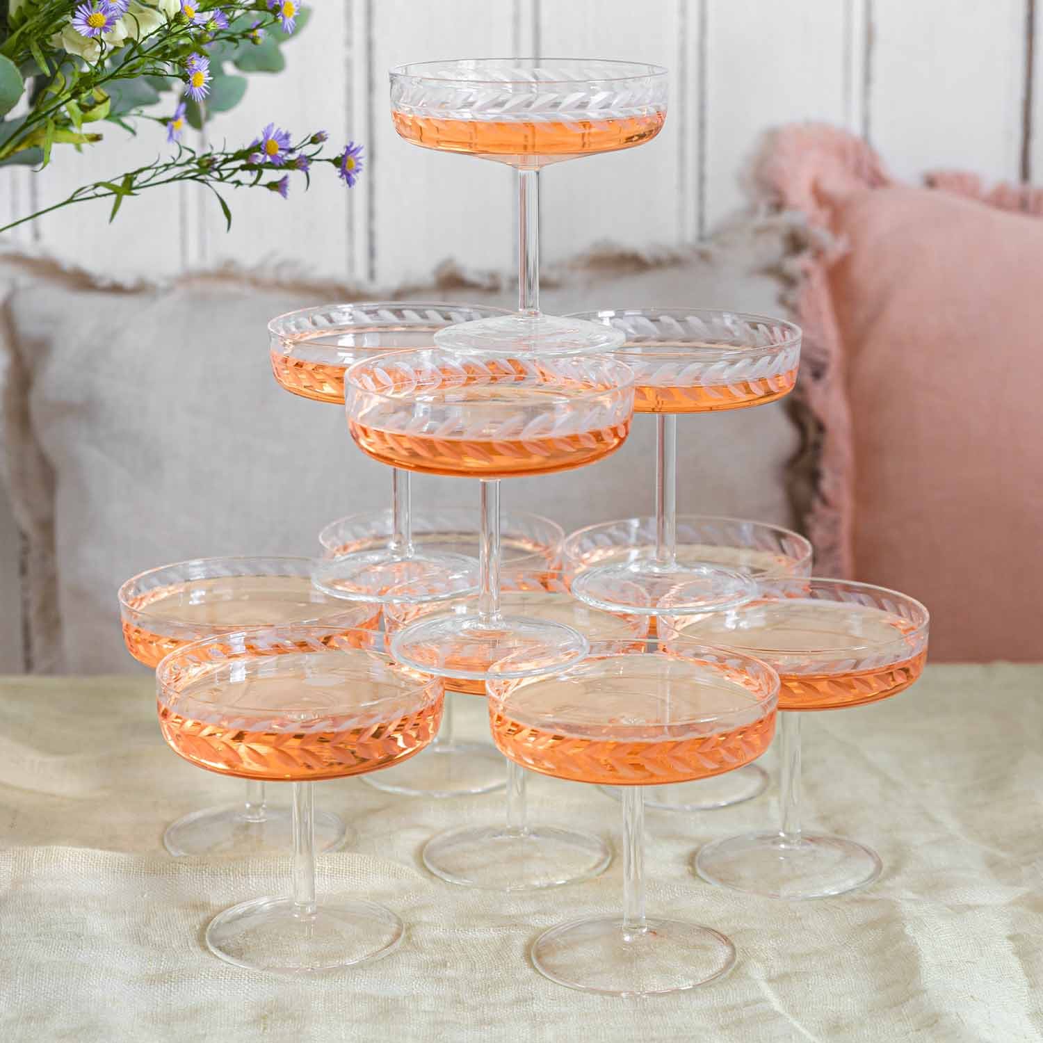 Set di bicchieri da champagne in cristallo con motivo delicato e bevanda rosa sul tavolo