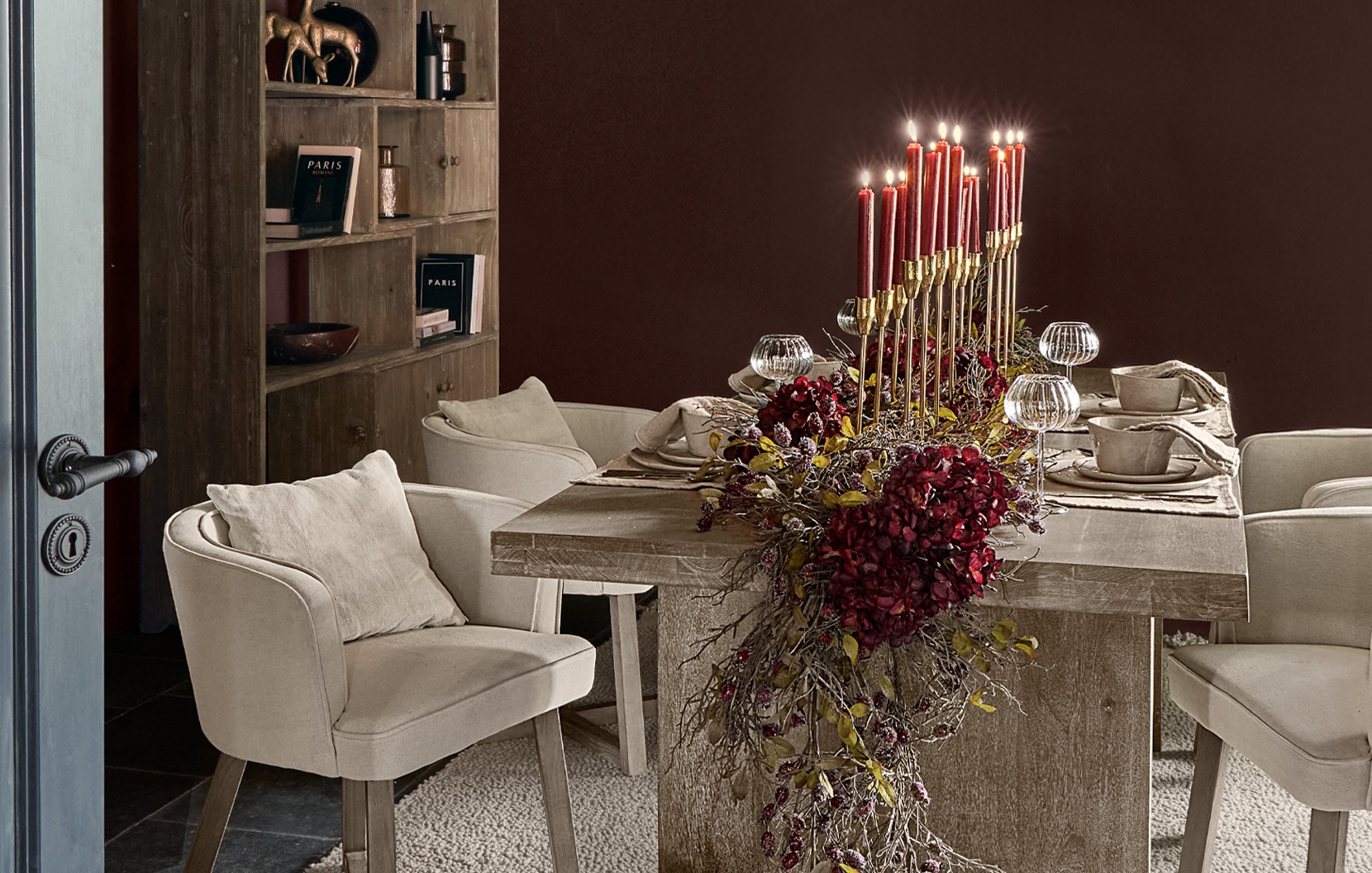 Sala da pranzo con tavolo in legno, poltrone crema e decorazione centrale con candele rosse e fiori