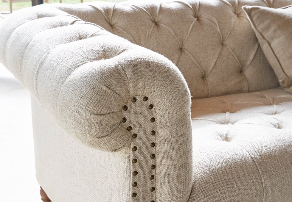 Divano classico beige in tessuto con schienale capitonné e chiodi decorativi per soggiorno
