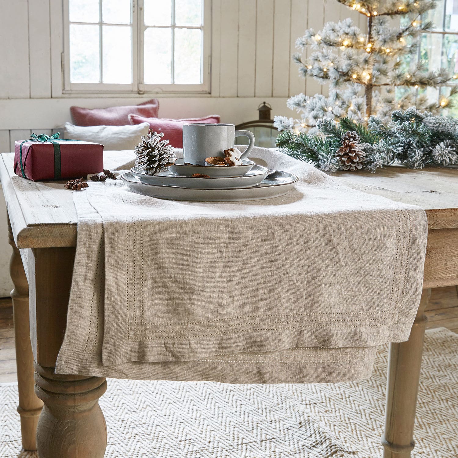 Runner Brion Runner da tavola in lino beige su tavolo in legno con decorazioni natalizie e stoviglie grigie
