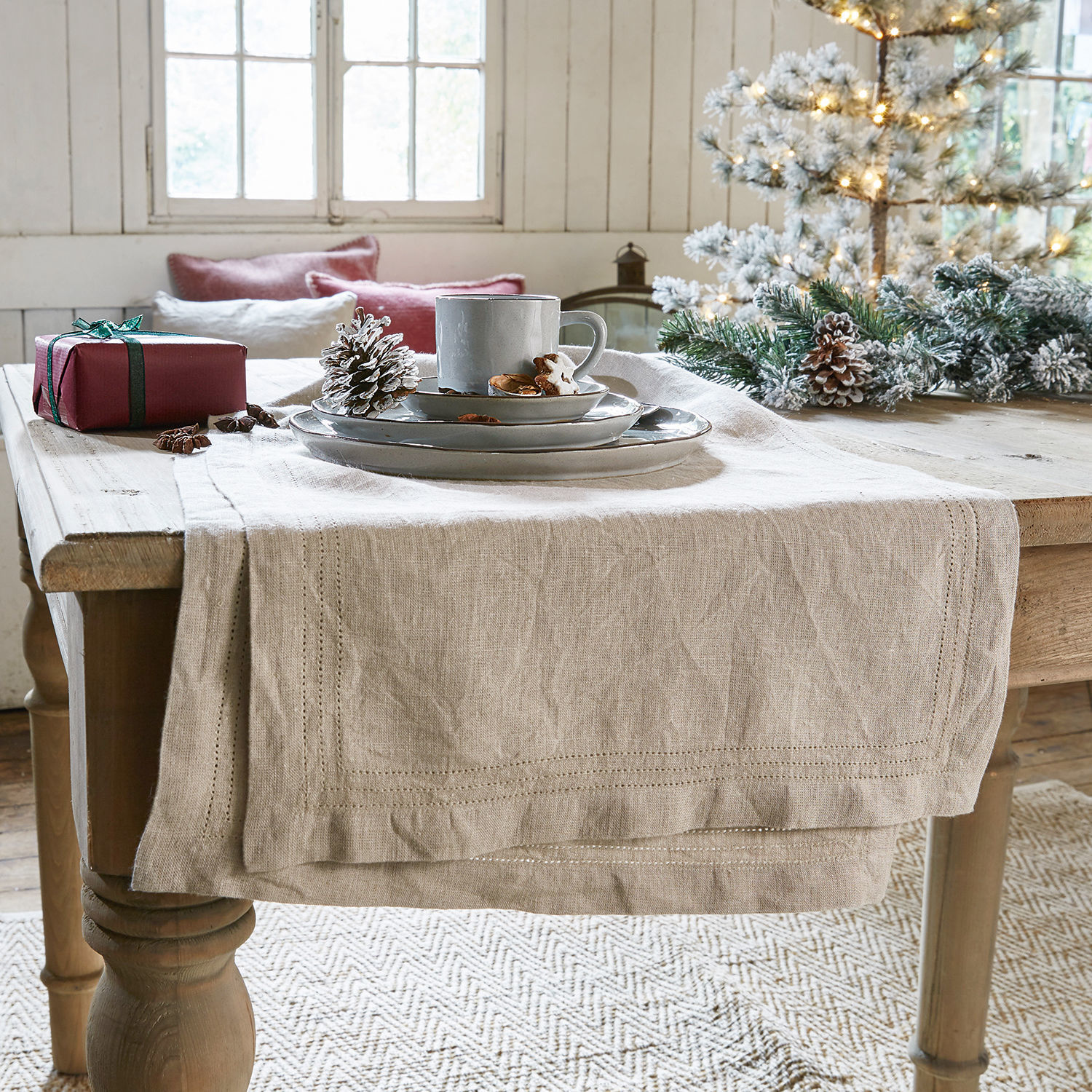 Runner Brion Runner da tavola in lino beige su tavolo in legno con decorazioni natalizie e stoviglie grigie