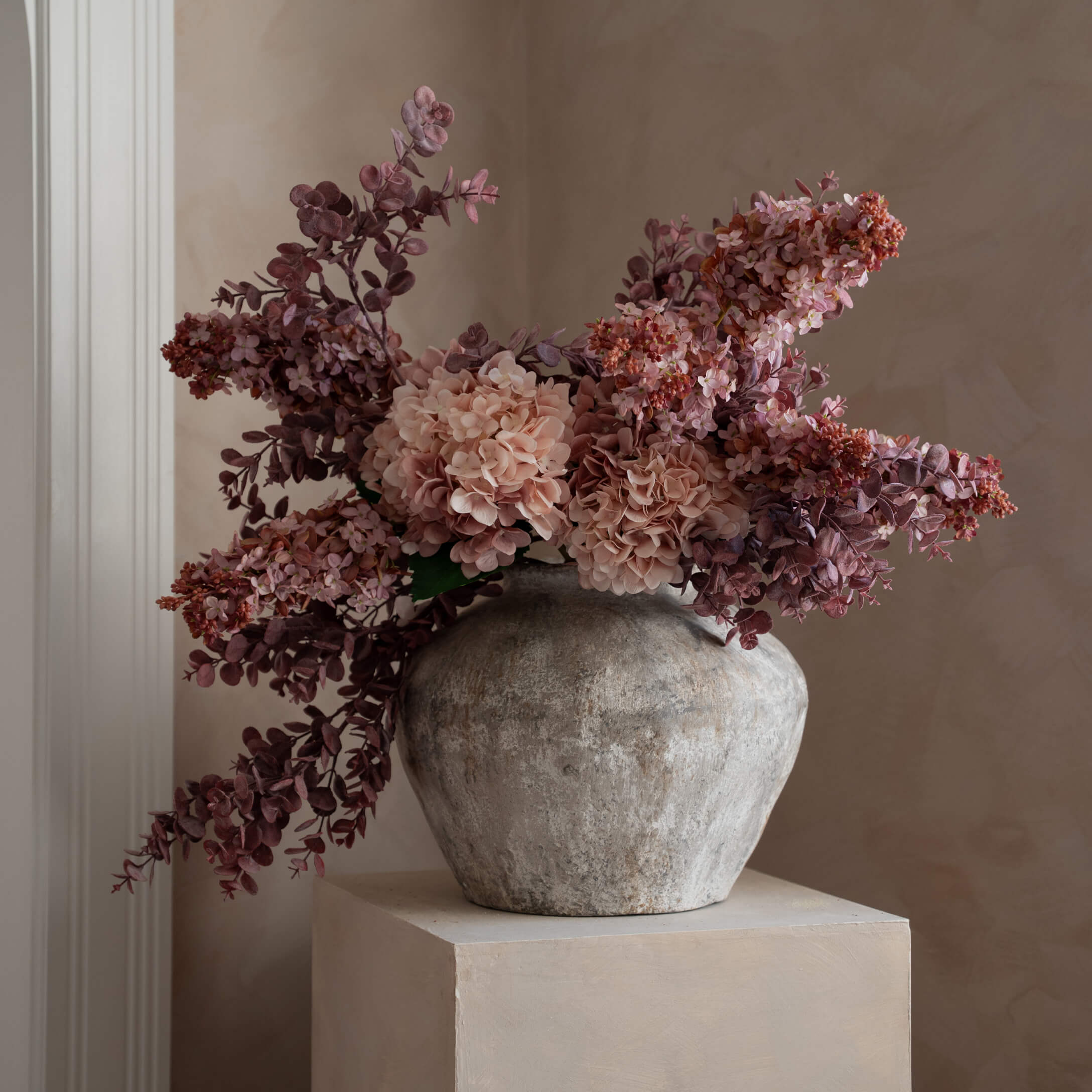 Vaso decorativo in pietra grigia con fiori artificiali rosa e viola per arredamento interno