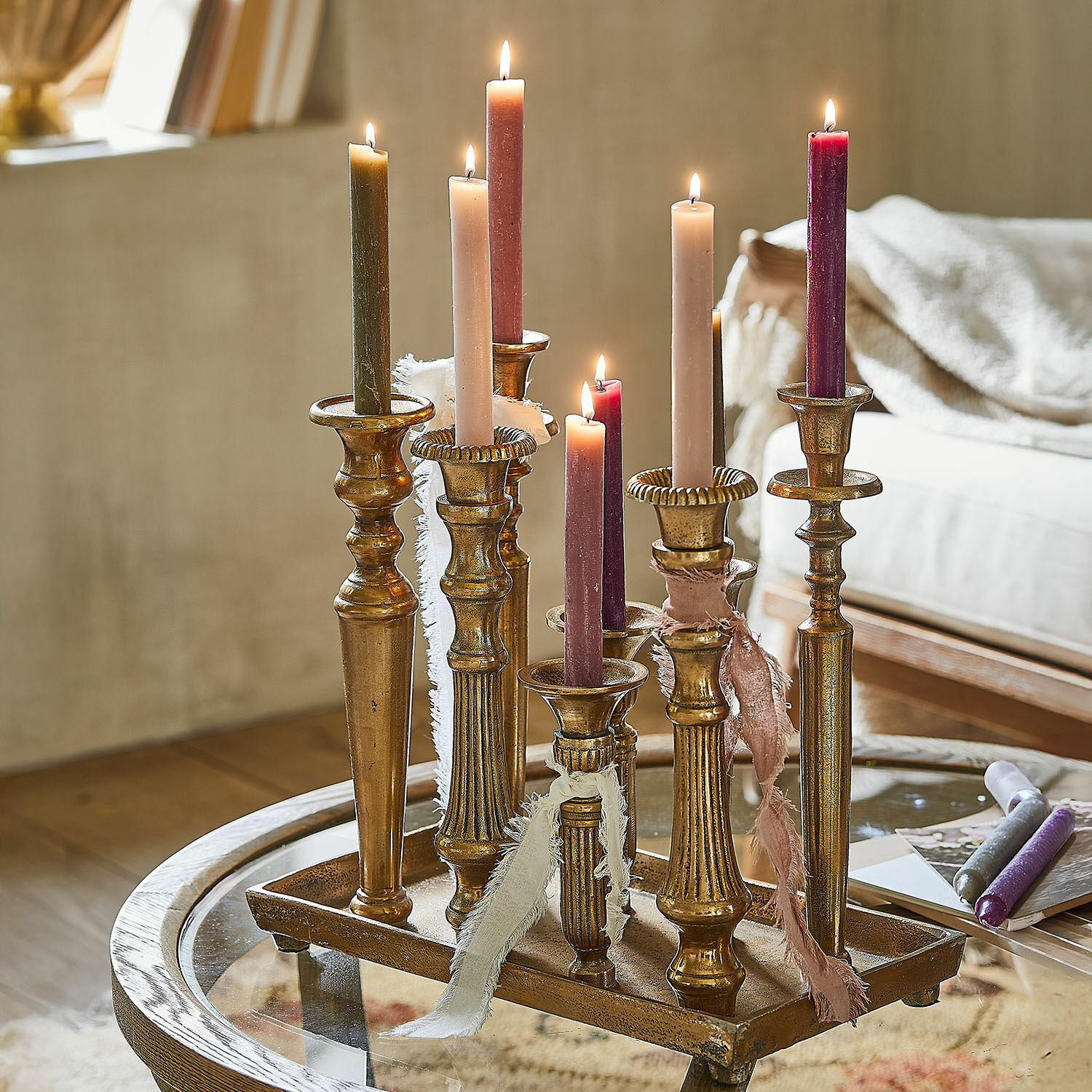 Vassoio portacandele Chavelot Set di candelabri in metallo dorato con candele colorate accese su tavolo in vetro