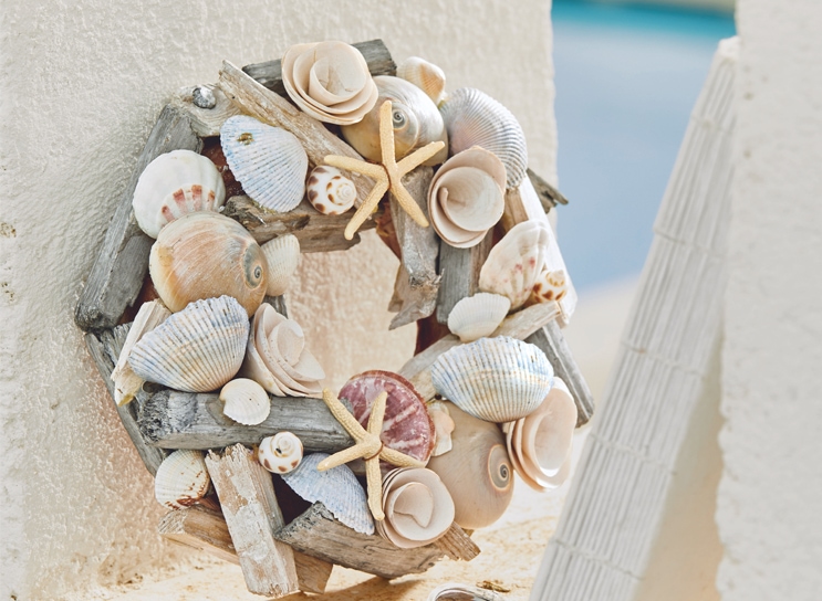 Corona decorativa in legno e conchiglie beige e azzurro chiaro, stile marinaro per la casa.