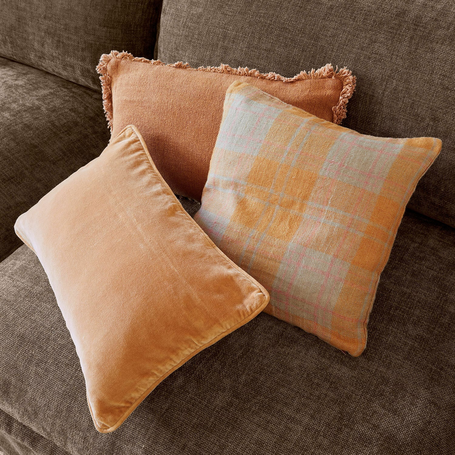 Set di 3 copricuscini Léonille Tre cuscini decorativi arancioni su divano marrone per un soggiorno accogliente