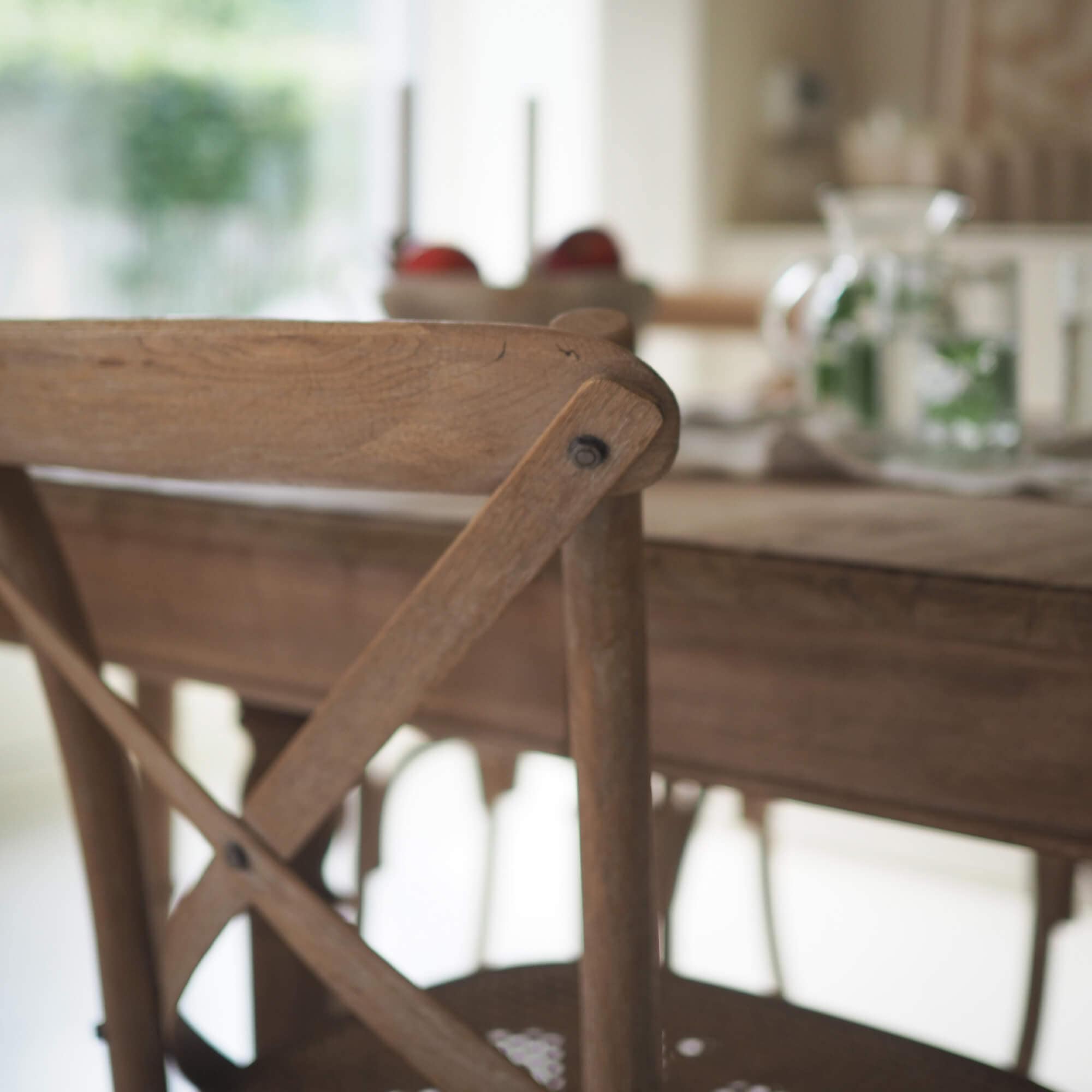 Sedia in legno chiaro con schienale a X in una sala da pranzo accogliente e luminosa