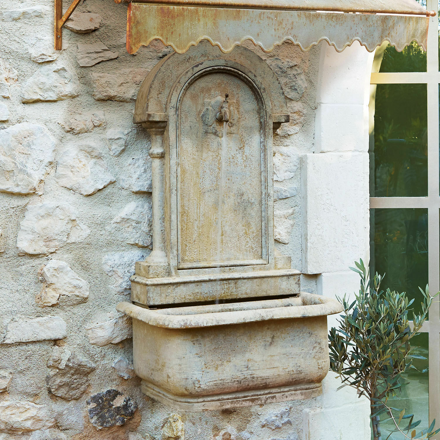 Fontana da parete Ivera Fontana da parete decorativa in pietra beige con copertura metallica arrugginita e getto d'acqua