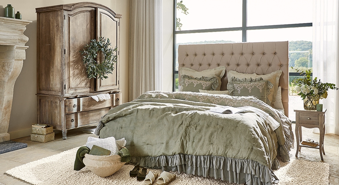 Camera accogliente con testiera imbottita e biancheria da letto in lino verde e grigio, atmosfera naturale
