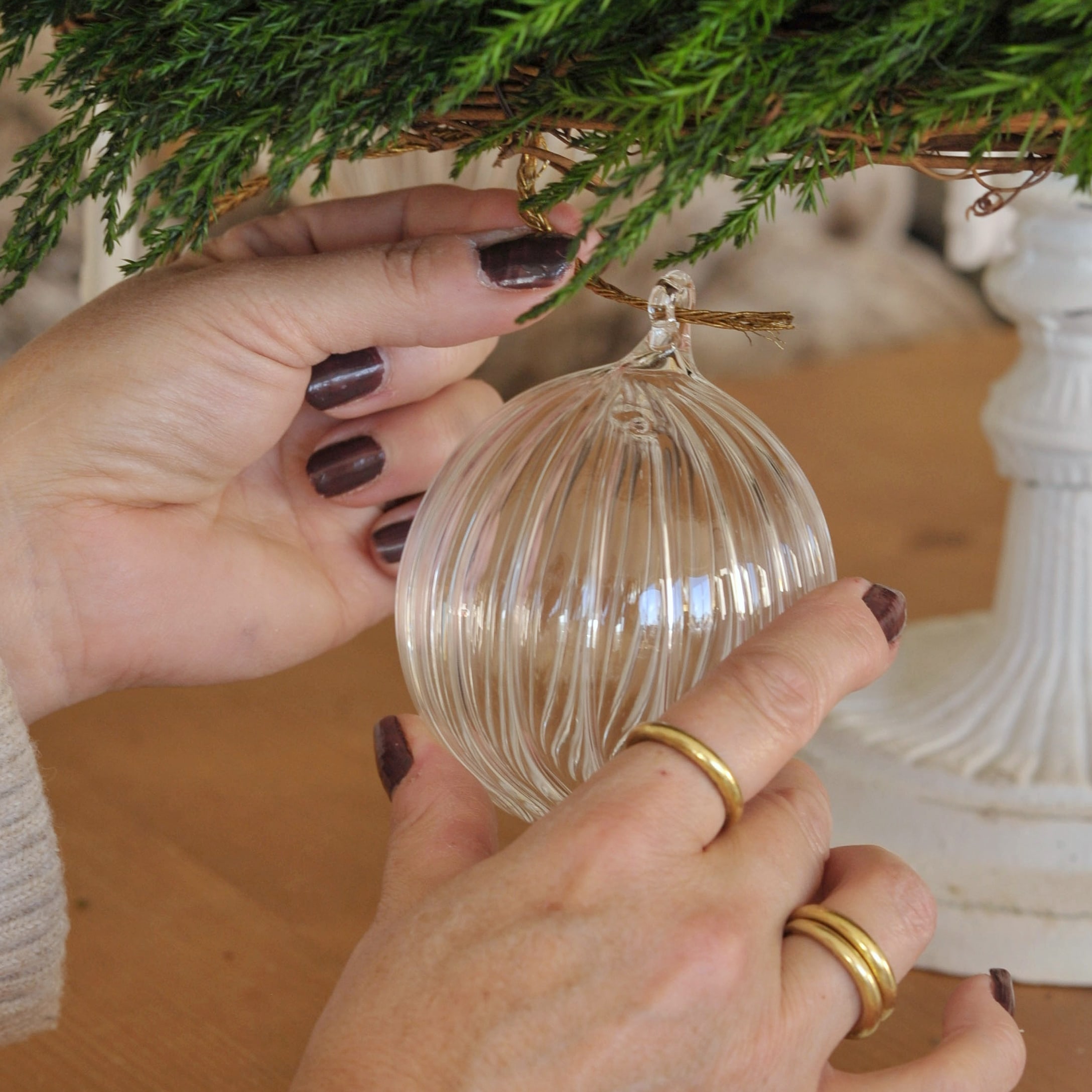 Pallina di Natale in vetro trasparente con scanalature appesa a un ramo verde di decorazione natalizia