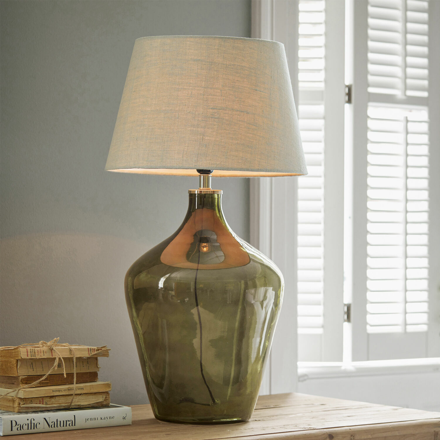 Lampada da tavolo Morazan Lampada da tavolo in vetro verde con paralume beige su tavolo in legno con libri