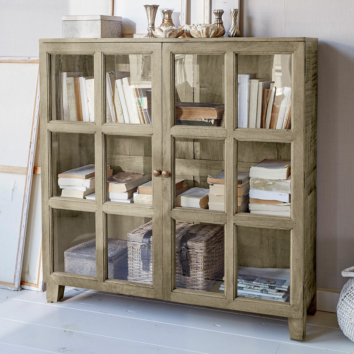 Mobile basso con ante in vetro Stoneham Vetrina in legno beige con ante in vetro, piena di libri e decorazioni, mobile elegante per soggiorno