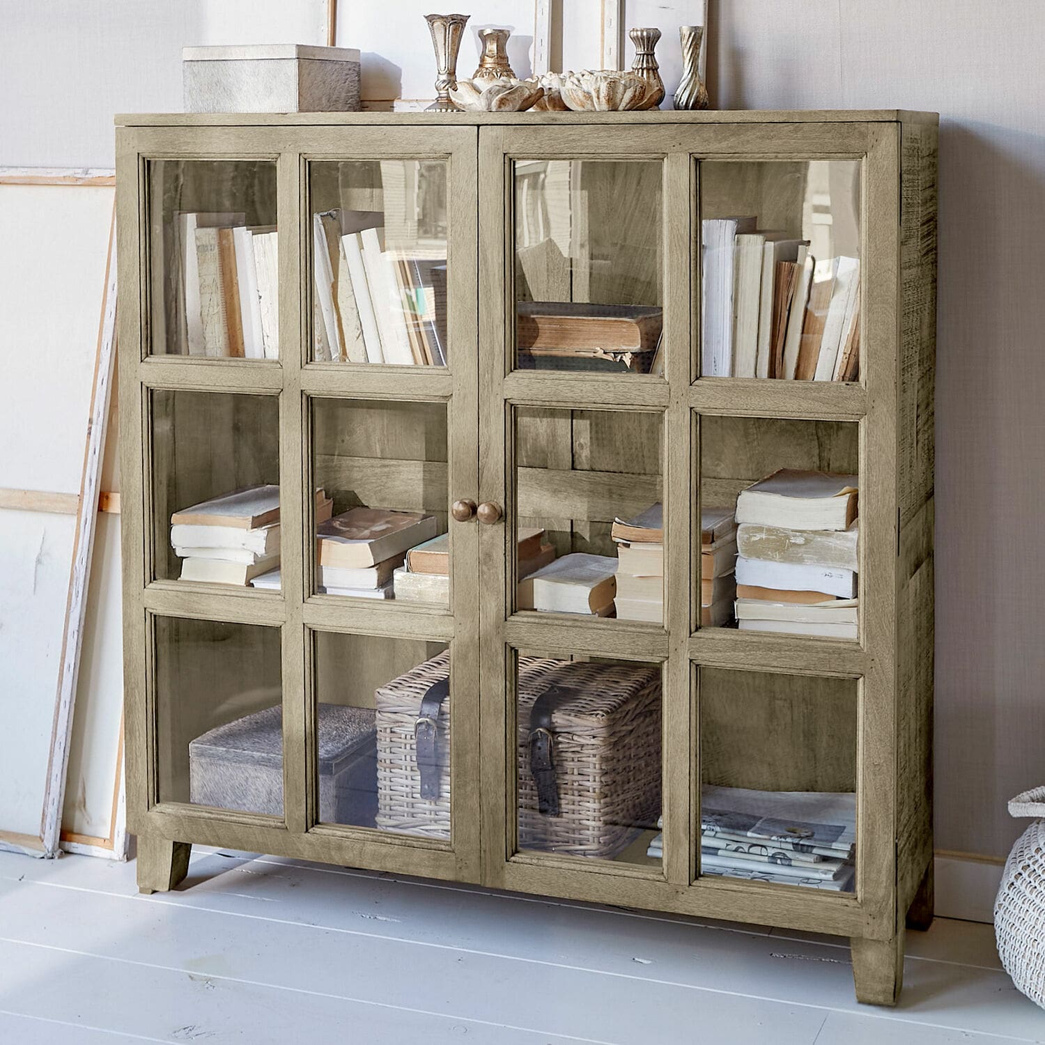 Mobile basso con ante in vetro Stoneham Vetrina in legno beige con ante in vetro, piena di libri e decorazioni, mobile elegante per soggiorno