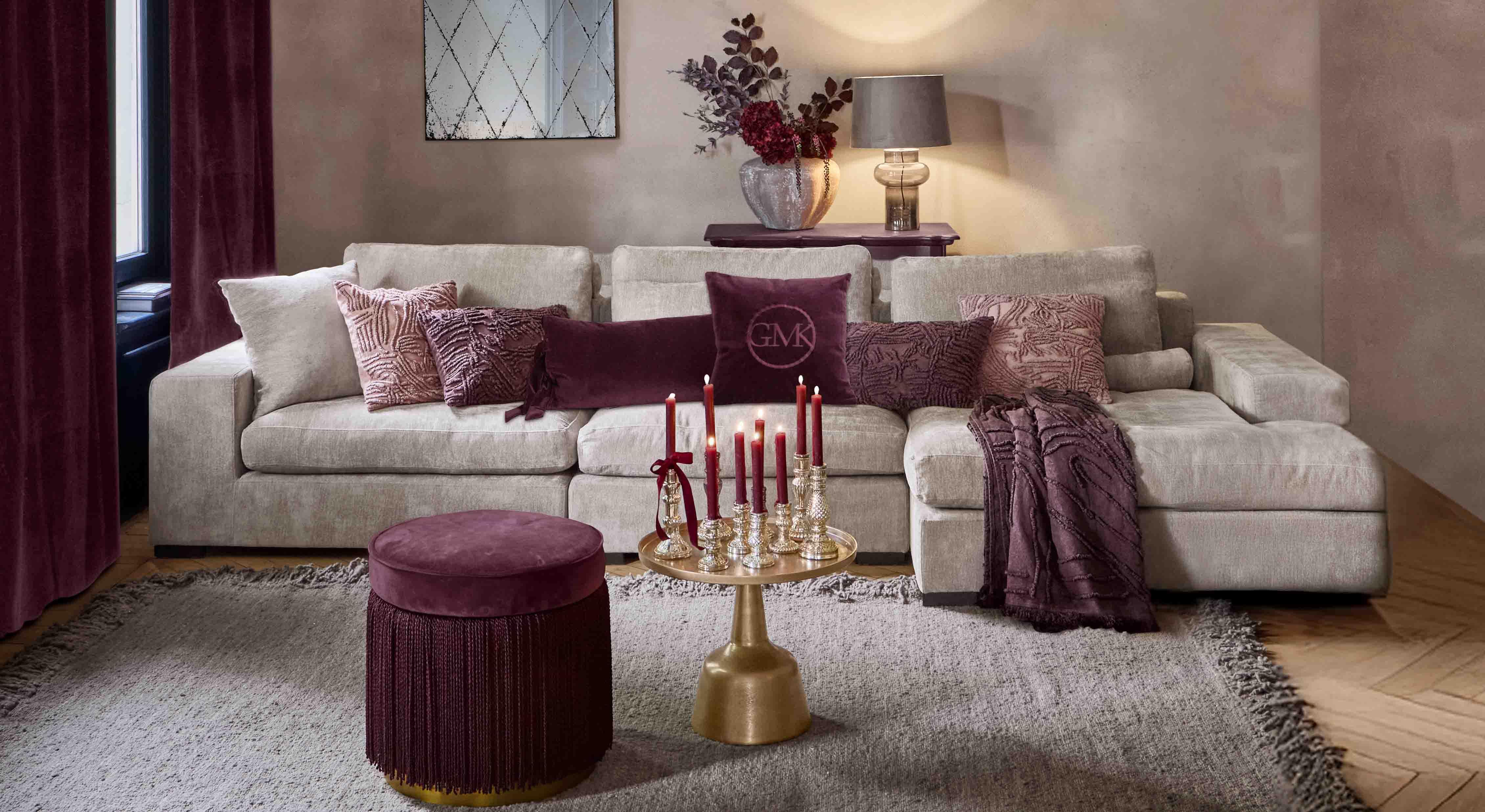 Divano beige con cuscini morbidi e dettagli bordeaux in soggiorno elegante con lampada e specchio
