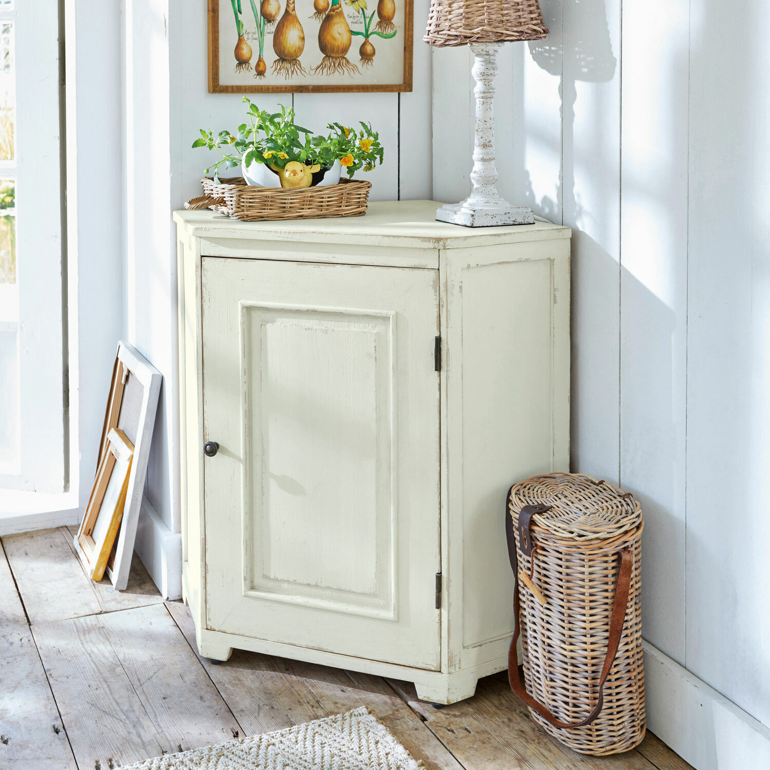 Comò angolare Yurielka Mobile in legno crema con una porta stile vintage in stanza luminosa con cesto in vimini