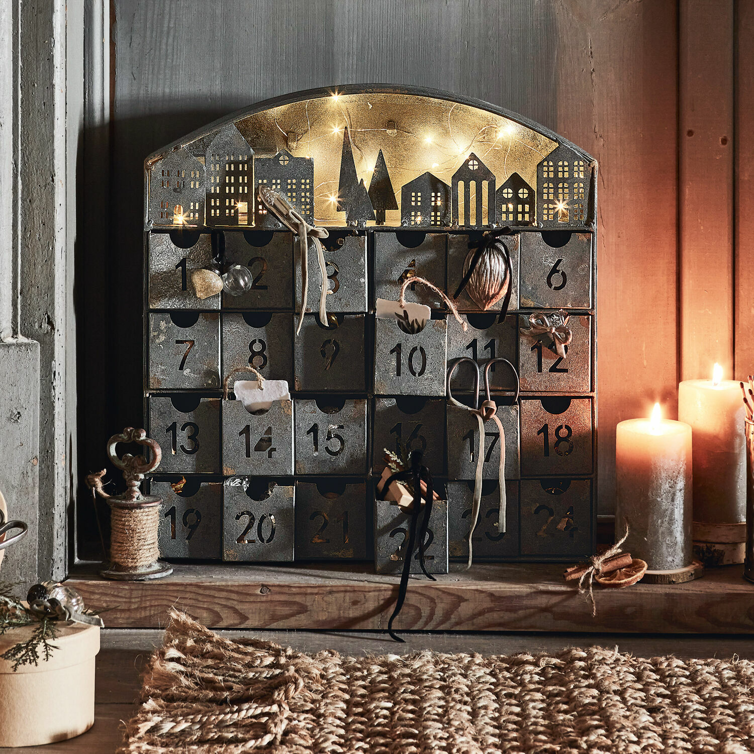 Calendario dell’Avvento Léran Calendario dell'Avvento in metallo con 24 cassetti numerati e decorazioni di casette illuminate da candele