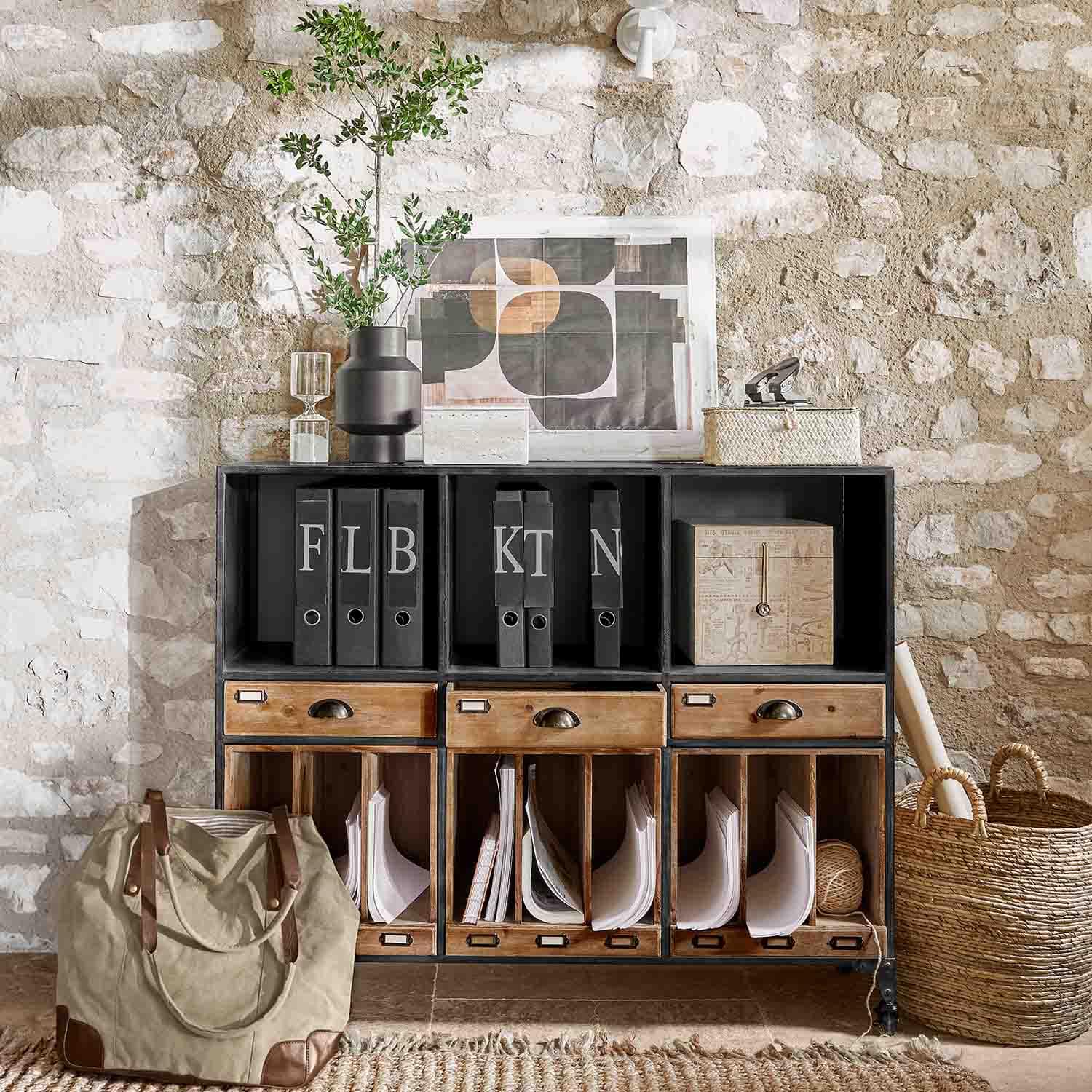 Mobile nero in metallo e legno con cassetti e raccoglitori davanti a muro in pietra stile loft