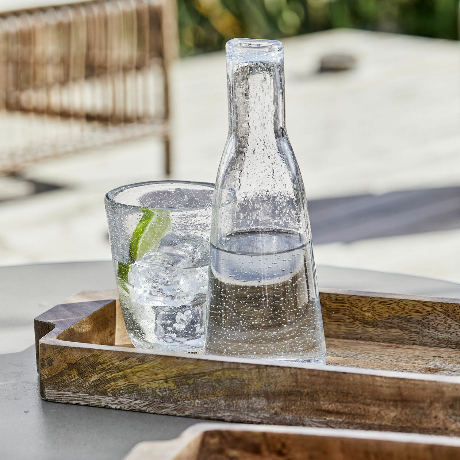 Caraffa Parilly Caraffa di vetro e bicchiere con ghiaccio e lime su vassoio in legno all'aperto