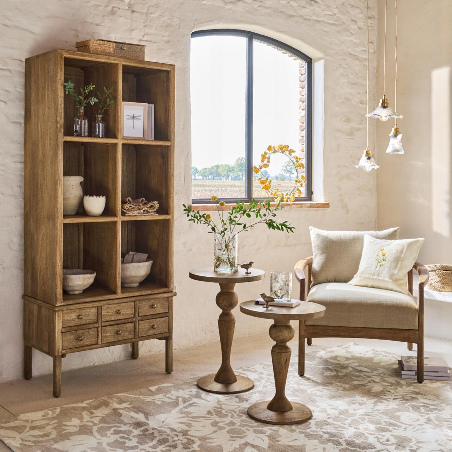 Mobile in legno con cassetti e tavolini in colore naturale in soggiorno luminoso con poltrona beige