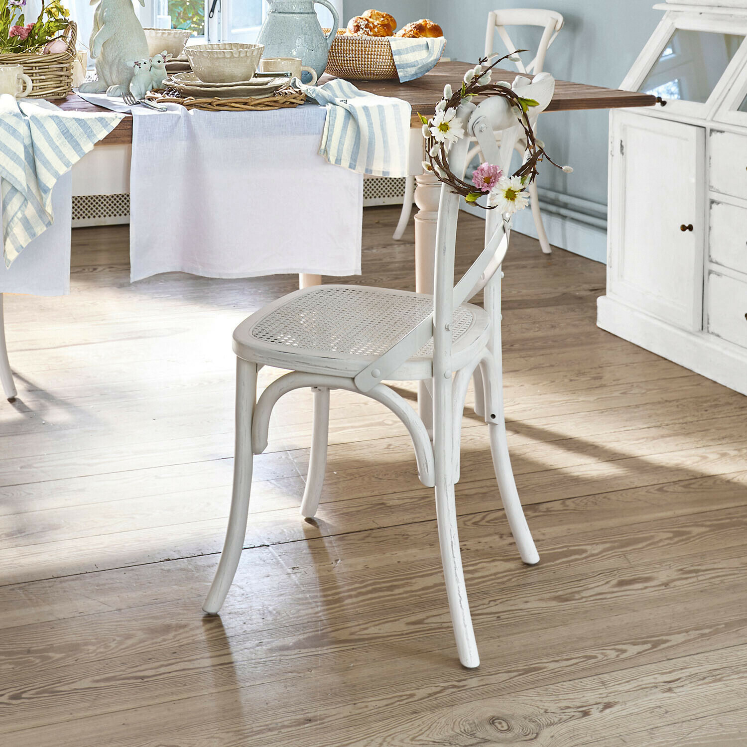 Sedia Kary Sedia in legno bianco con seduta intrecciata e corona floreale decorativa in sala da pranzo luminosa
