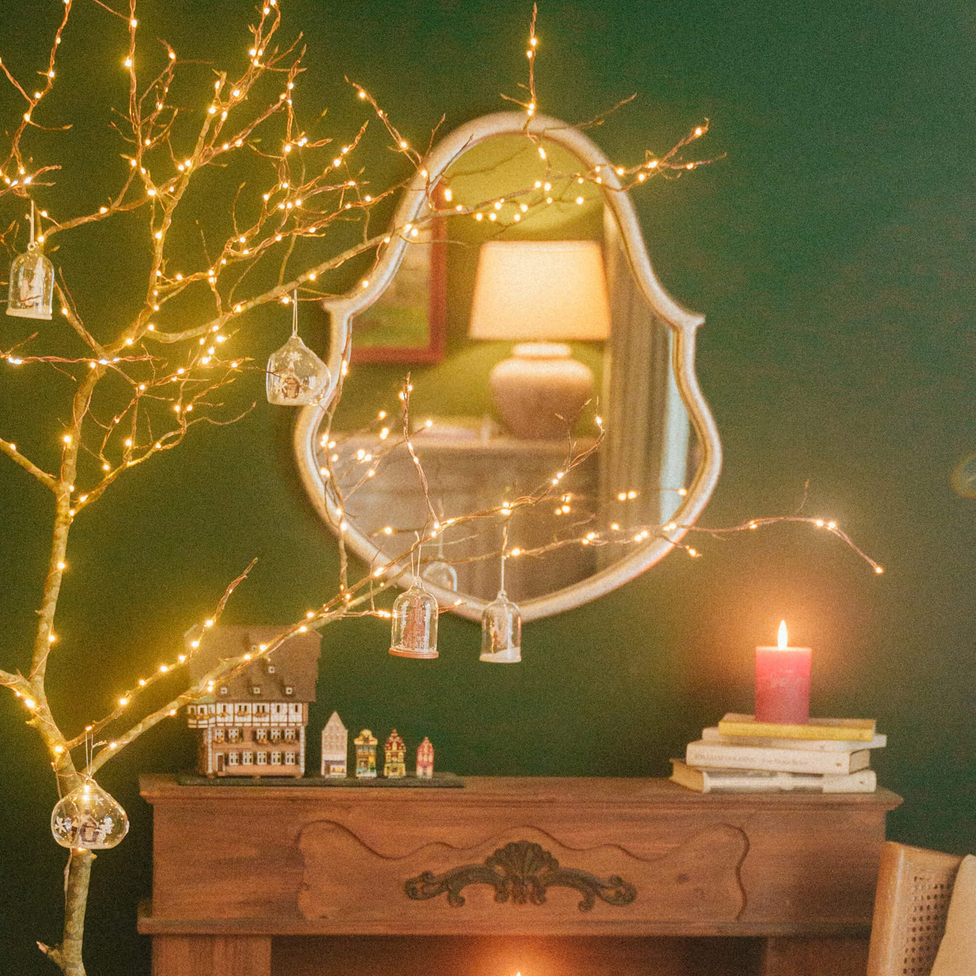 Rami decorativi con luci LED e ornamenti in vetro davanti a specchio e camino in soggiorno