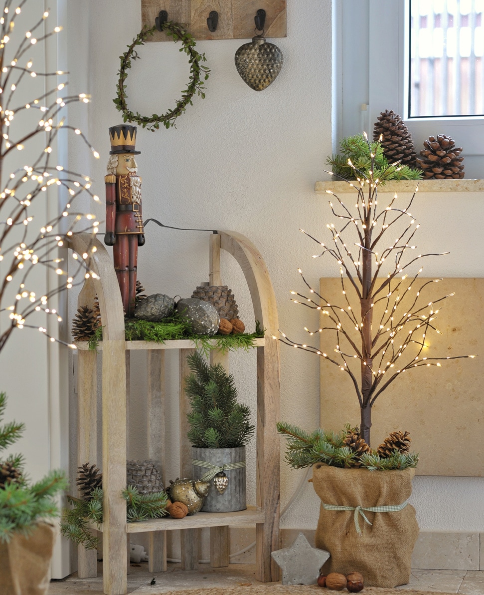 Albero luminoso LED decorativo in sacco di juta con pigne e rami verdi, decorazione natalizia accogliente.