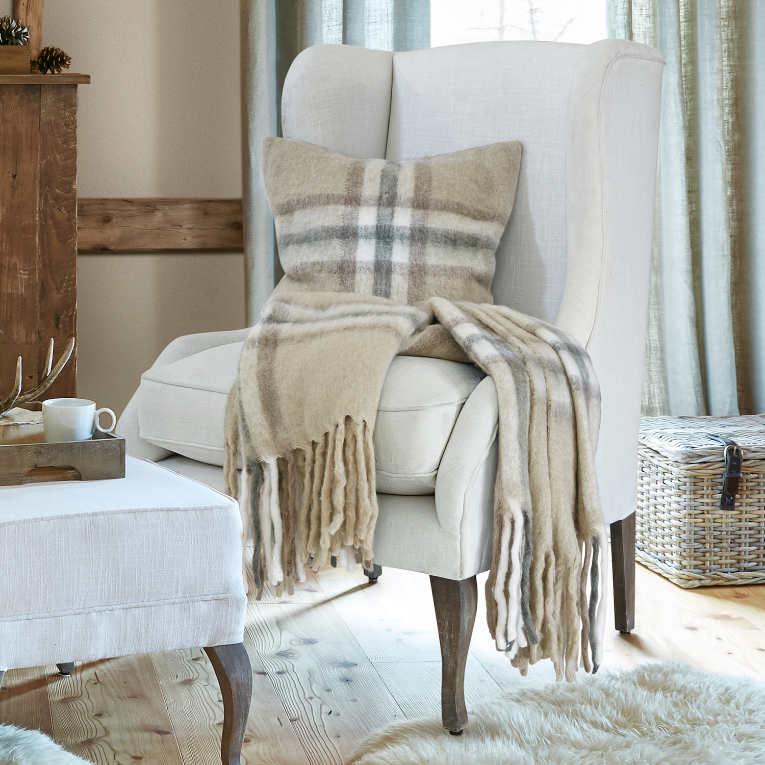 Plaid e cuscino in lana beige a quadri su poltrona crema in soggiorno accogliente